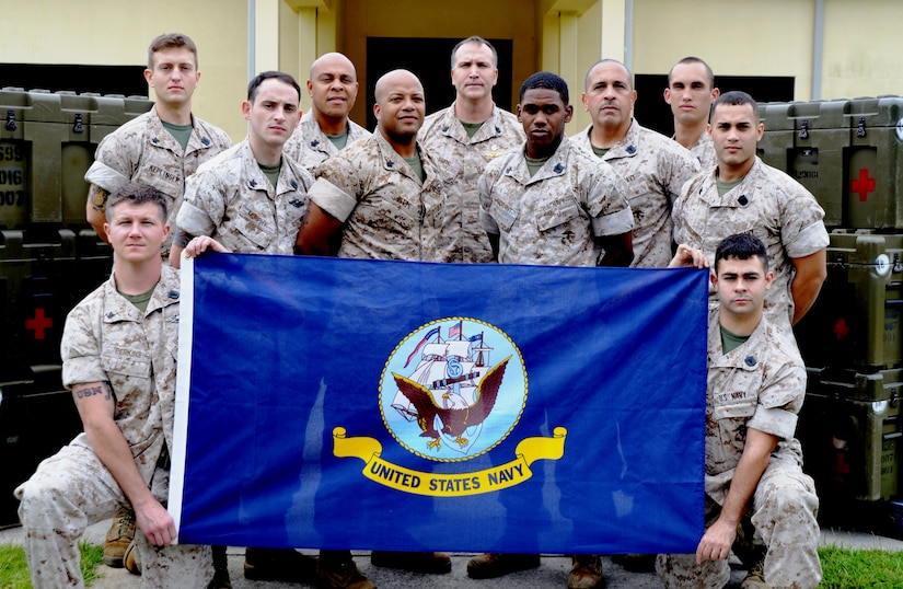The original Plankowners of Medical Logistics Platoon, Detachment 3: (Left to right with flag) Petty Officer 3rd Class Monty Perkins and Petty Officer 3rd Class Garrett Minato. (Second row left to right) Petty Officer 2nd Class Timothy Murphy, Petty Officer 1st Class Andre Pitts, Petty Officer 2nd Class Marquis Morant and Petty Officer 2nd Class Orlando Cardona. (Back row left to right) Petty Officer Second Class Tate Keplinger, Petty Officer First Class Steven Mansion, Chief Petty Officer Jim Smith, Petty Officer 3rd Class Carlos Cintron-Vega and Petty Officer Second Class Nicholas Perez. Not pictured is Lt. David Guajardo. A Plankowner is a Sailor who is an original member of a newly established unit or vessel. MEDLOG Detachment 3 “stood up” as a unit in October 2013. (U.S. Air Force photo/Eric Sesit)