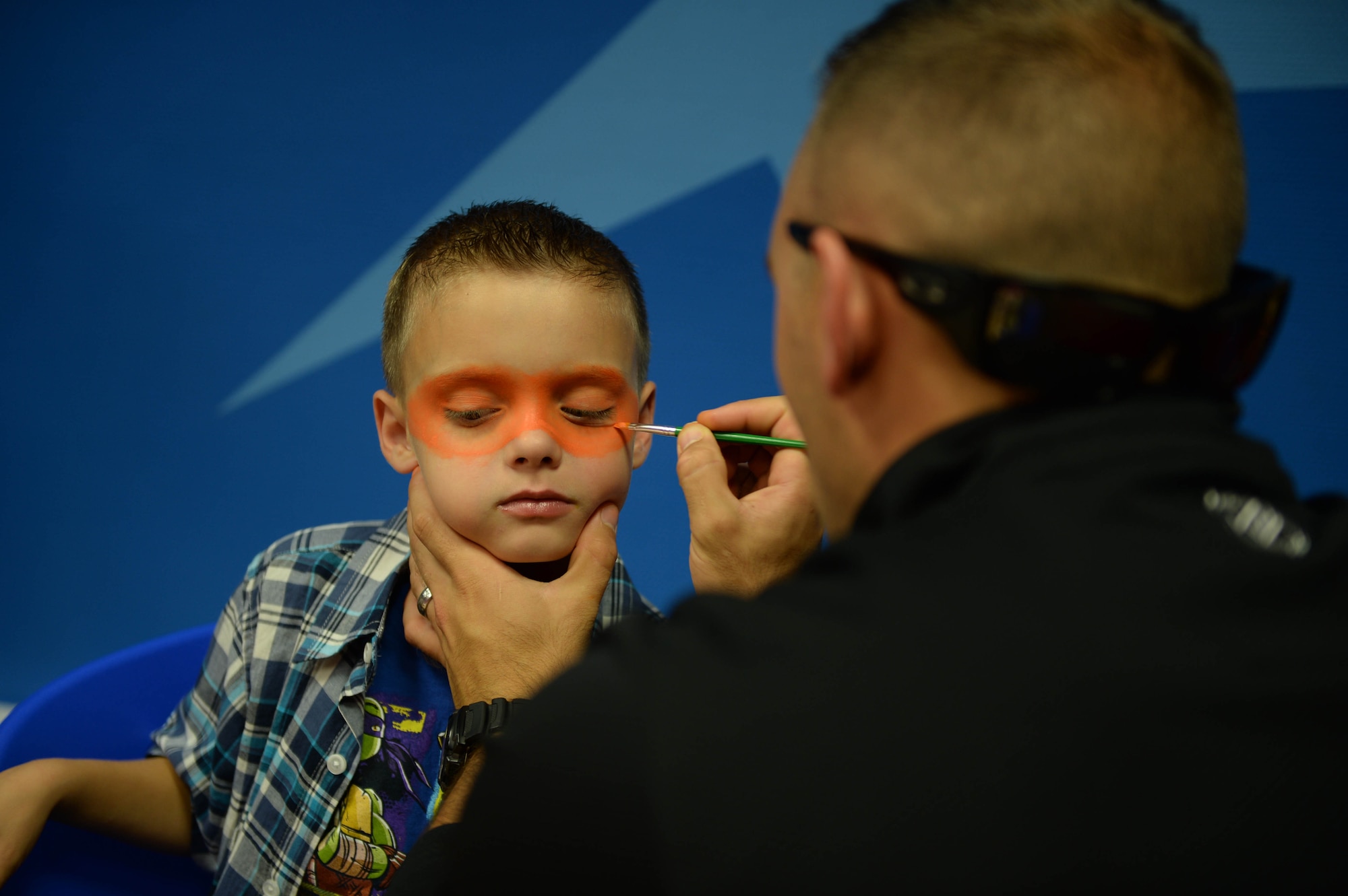 U.S. Air Force Airman 1st Class Ryan Macri, a 606th Air Control Squadron radio frequency transmission journeyman, paints a mask on his son Zachary during Zachary’s birthday party Sept. 13, 2014, at Spandahlem Air Base, Germany. The Macris celebrated Zachary’s birthday early, so Ryan could attend before leaving on a deployment. (U.S. Air Force photo by Airman 1st Class Dylan Nuckolls/Released)