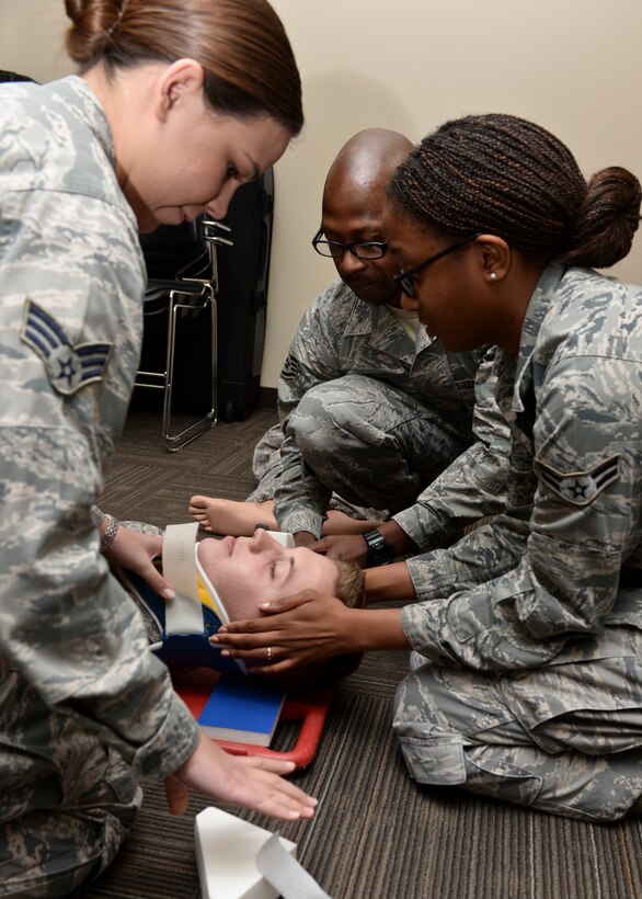 Senior Airman Morissa Martin, Airman 1st Class Chacity Jones and Staff Sgt. Ricky Dunbar, 28th Medical Operations Squadron aerospace medical services technicians, stabilize Airman 1st Class Adam Heron, 28th MDOS aerospace medical services technician, onto a long spine board during emergency medical technician training at Ellsworth Air Force Base, S.D., Oct. 6, 2014. Emergency medical technicians are first to administer basic and emergency medical treatment to those injured during an emergency situation. (U.S. Air Force photo by Senior Airman Anania Tekurio/Released)