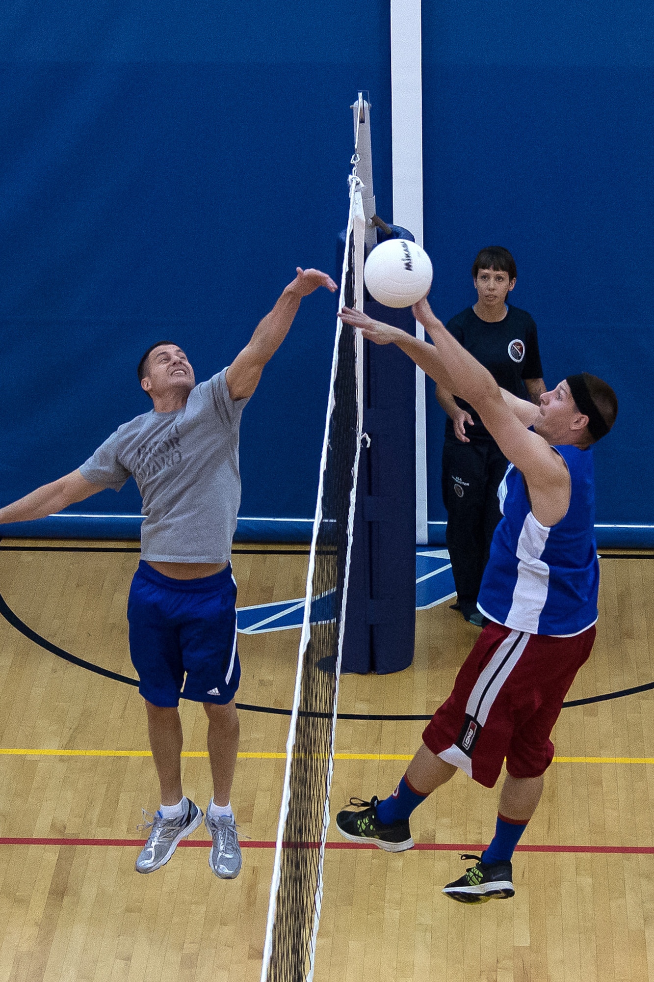 Master Sgt. Aaron Marley (left) and Senior Airman Timothy Geary (right) compete for a ball near the net during a volleyball game at the base Fitness and Sports Center between Airman Leadership School students and Hanscom Senior NCOs Oct. 2, while Staff Sgt. Ashley Lerke, an ALS instructor, looks on. The volleyball game is part of ALS heritage and fostering relationships between Senior NCOs and future leaders of the AF. ALS is a five week-long Air Force PME class designed to develop Airmen into effective front-line supervisors. The curriculum focuses on developing leadership abilities as well as effective communication. (U.S. Air Force photo by Mark Herlihy)