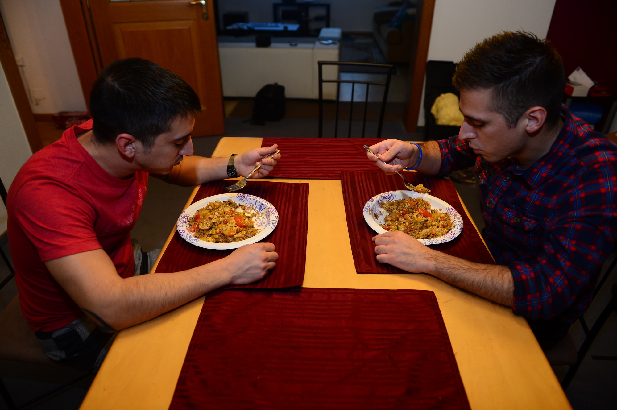 U.S. Air Force Senior Airman Edward Lomelin, 606th Air Control Squadron radio frequencies transmission systems technician and native of Austin, Texas, and U.S. Air Force Airman 1st Class Chris Lomelin, 606th ACS power production technician and native of Austin, Texas, eat dinner together at their home in Bitburg, Germany, Oct. 1, 2014. Edward, Chris’ older brother, helped to prepare Chris for his first deployment to Southwest Asia. This will be Edward’s fourth deployment. (U.S. Air Force photo by Airman 1st Class Kyle Gese/Released)