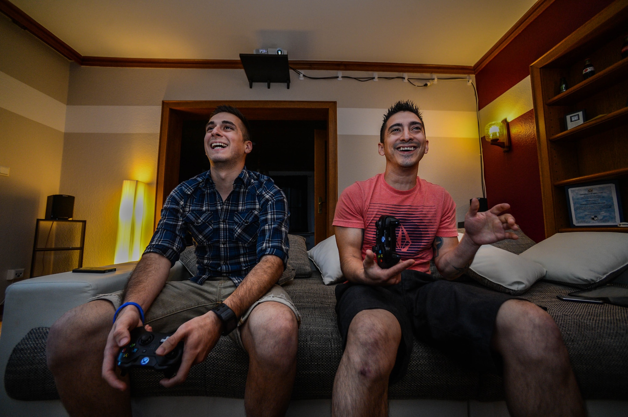 U.S. Air Force Senior Airman Edward Lomelin, 606th Air Control Squadron radio frequencies transmission systems technician and native of Austin, Texas, and U.S. Air Force Airman 1st Class Chris Lomelin, 606th ACS power production technician and native of Austin, Texas, play video games together at their home in Bitburg, Germany, Sept. 27, 2014. The 606 ACS is a self-contained mobile combat unit with Airmen covering more than 21 specialties maintaining over $170 million worth of equipment. The squadron routinely trains to prepare for deployments. The Lomelins deployed together to support Operation Enduring Freedom. (U.S. Air Force photo by Airman 1st Class Kyle Gese/Released)