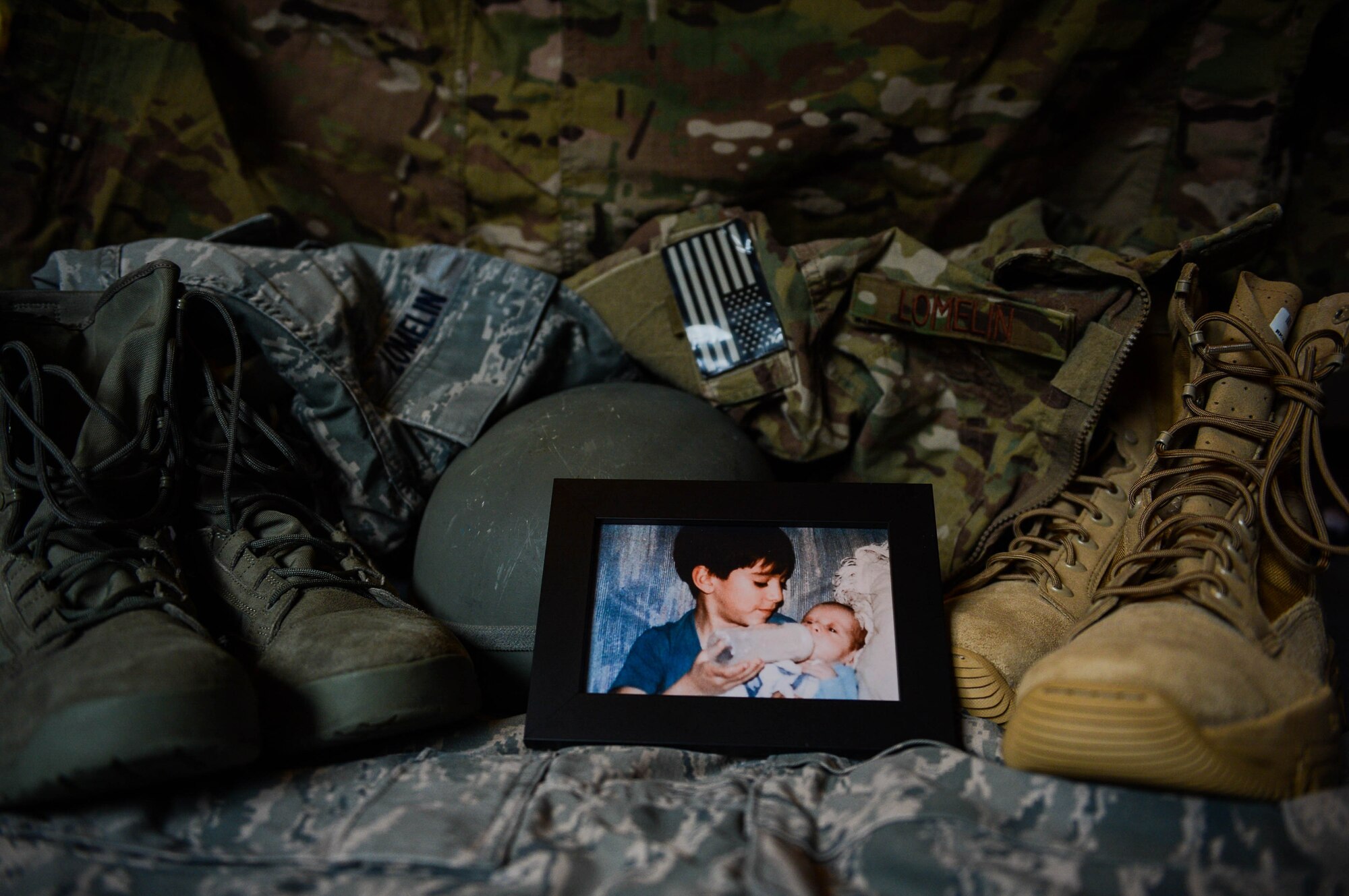 A photograph of U.S. Air Force Senior Airman Edward Lomelin, 606th Air Control Squadron radio frequencies transmission systems technician and native of Austin, Texas, feeding his younger brother U.S. Air Force Airman 1st Class Chris Lomelin, 606th ACS power production technician and native of Austin, Texas, rests on their uniforms at their home in Bitburg, Germany, Sept. 26, 2014. Edward and Chris recently prepared themselves to deploy to Southwest Asia in support of Operation Enduring Freedom. Both brothers are stationed together at Spangdahlem Air Base, Germany, and operate out of the same squadron. (U.S. Air Force photo by Airman 1st Class Kyle Gese/Released)