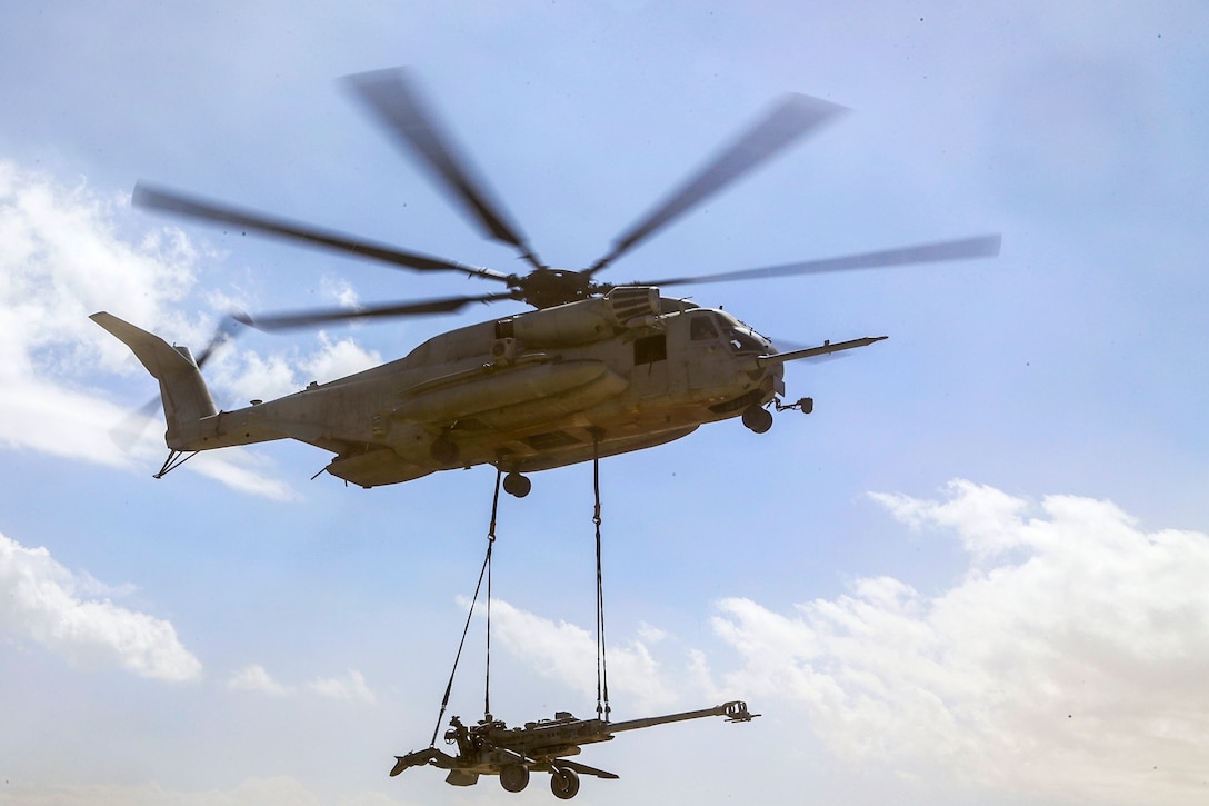 A CH-53E Super Stallion helicopter lifts a M777 howitzer during an ...