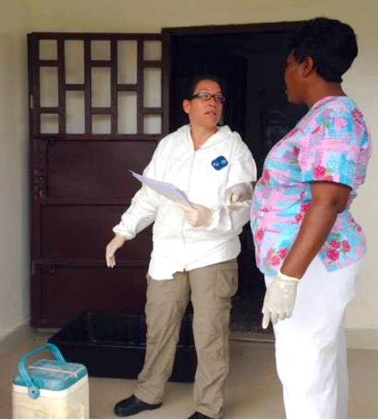 U.S. Navy Lt. Andrea McCoy explains how to submit samples to the Naval Medical Research Center mobile laboratory to a health worker in Liberia, Oct. 7, 2014.