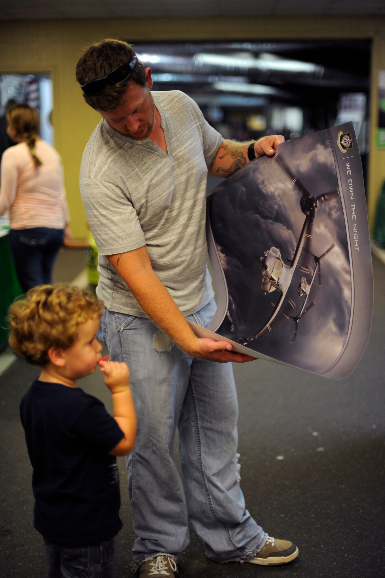 Jake McGonegal shows his son, Jameson, a poster of CV-22 Ospreys during the 2014 Northwest Florida Tri-County Fair at the Fort Walton Beach Fairgrounds in Fort Walton Beach, Fla., Oct. 2, 2014. The 1st Special Operations Wing participated in the fair by providing informational booths to inform the public about Hurlburt Field's mission. (U.S. Air Force photo/Staff Sgt. Sarah Hanson)
