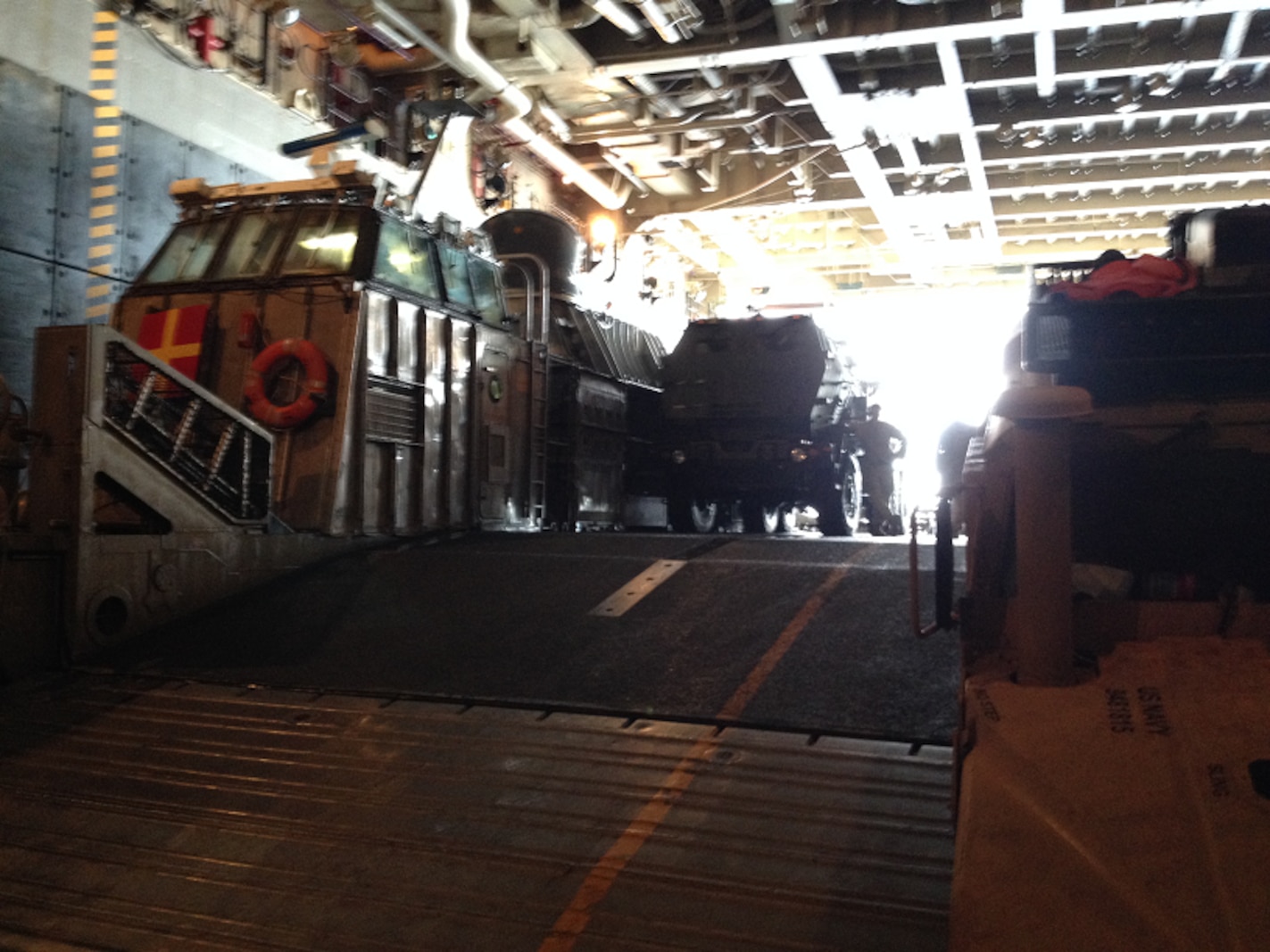 A M142 HIMARS launcher and a M1114 HMMWV from Battery R are loaded onto a Landing Craft Air Cushion (LCAC) in the well deck of the USS Peleiu (LHA-5).  