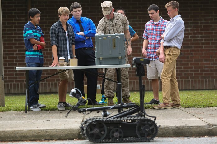Staff Sgt. Jeff Ehnen, a section leader with Explosive Ordnance Disposal Company, 8th Engineer Support Battalion, 2nd Marine Logistics Group, demonstrates the use of robots to students of Lejeune High School, Oct. 3, 2014, aboard Marine Corps Base Camp Lejeune, N.C.  Approximately 60 students, ranging from freshmen to seniors, packed the classroom to hear how the Marines use robotics on the battlefield and how engineering can better people’s lives. The school requested the Marines give the demonstration because the students are beginning their robotics curriculum of the Bio-Tech Department course of study.  (U.S. Marine Corps photo by Cpl. Michael Dye / Released)