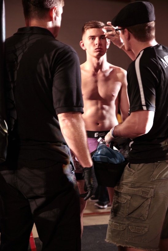 John Zimmer (center), a security specialist at Headquarters Battalion, Marine Forces Reserve, gets examined by a ringside physician moments before his fight at the Caged Warrior Championship V on Oct. 4, 2014, in Patterson, La. Zimmer’s coach, Collin Murray, places petroleum jelly on Zimmer’s face to prevent cuts during the fight.

