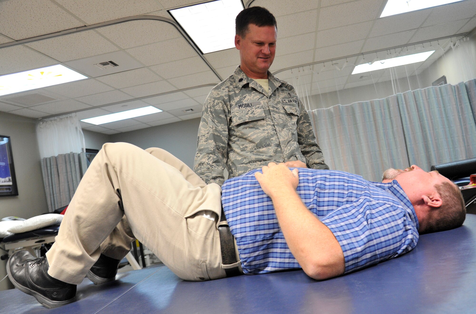 Lt. Col. Troy McGill, 92nd Medical Operations Squadron physical therapy flight commander, puts Rheet Norris, 92nd MDOS physical therapist, on the padded table at the medical clinic at Fairchild Air Force Base, Wash., Sept. 29, 2014. The 92nd Medical Group recently opened a physical therapy walk-in clinic, potentially allowing someone who obtains an injury to walk in for treatment the same day it occurs. (U.S. Air Force photo by Senior Airman Ryan Zeski)