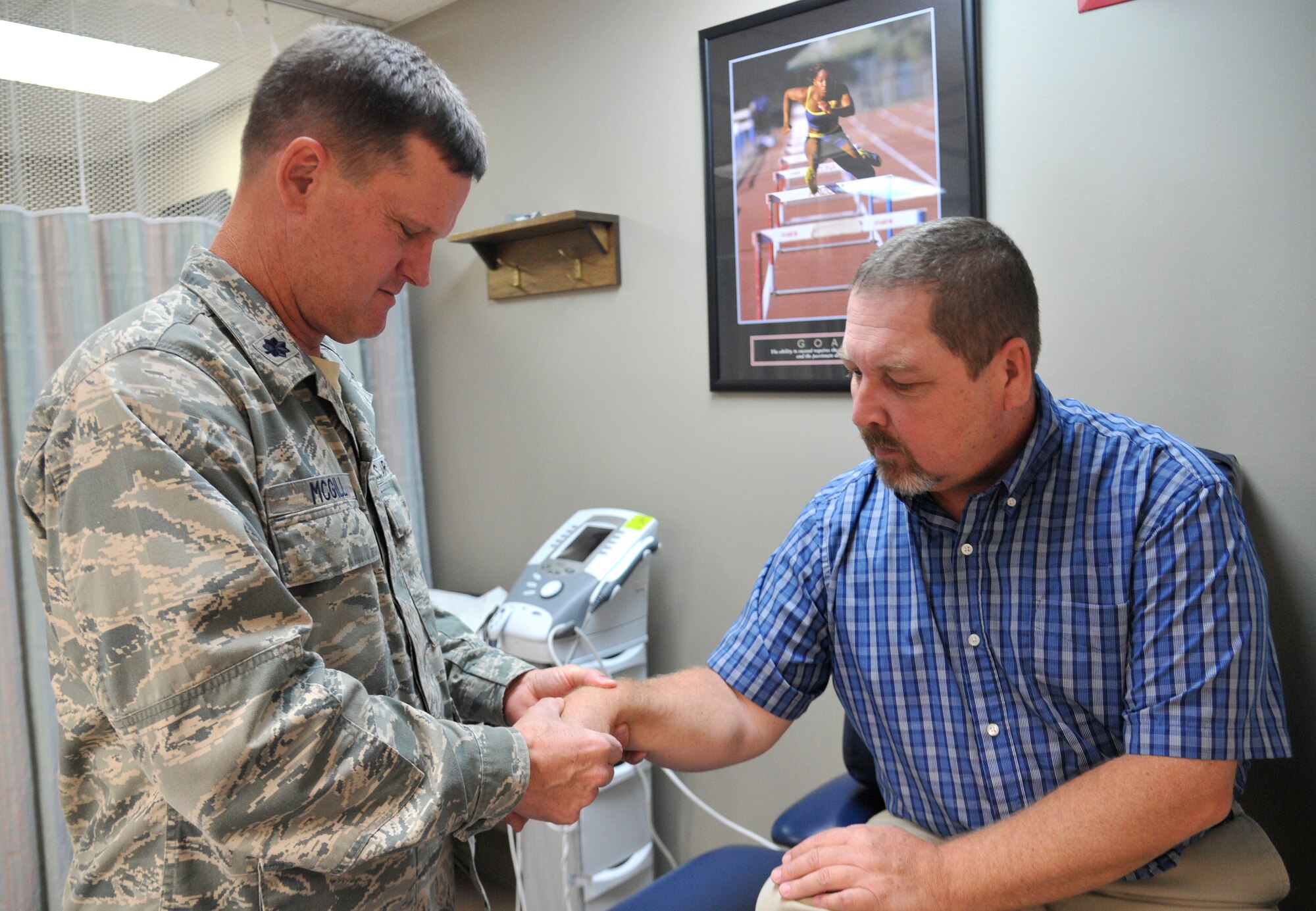 Lt. Col. Troy McGill, 92nd Medical Operations Squadron physical therapy flight commander, inspects the wrist of Rheet Norris, 92nd MDOS physical therapist, at the medical clinic at Fairchild Air Force Base, Wash., Sept. 29, 2014. The 92nd Medical Group recently opened a physical therapy walk-in clinic, potentially allowing someone who obtains an injury to walk in for treatment the same day it occurs. (U.S. Air Force photo by Senior Airman Ryan Zeski)
