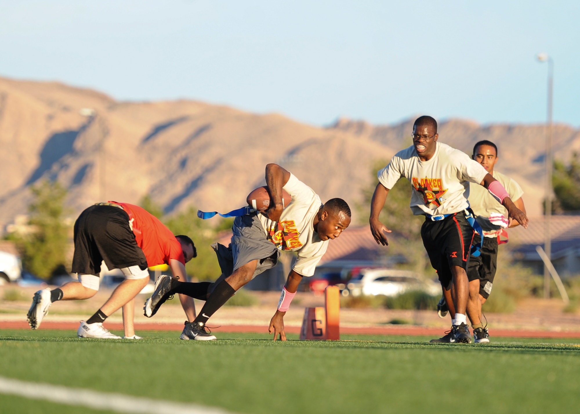 A member of the 757th Aircraft Maintenance Squadron Flankers team plunges toward the goal line during their game against the 757th AMXS Thunder team at Nellis Air Force Base, Nev., Oct. 6, 2014. The flag football season kicked off at Nellis AFB Oct. 1.(U.S. Air Force photo by Airman 1st Class Mikaley Towle)