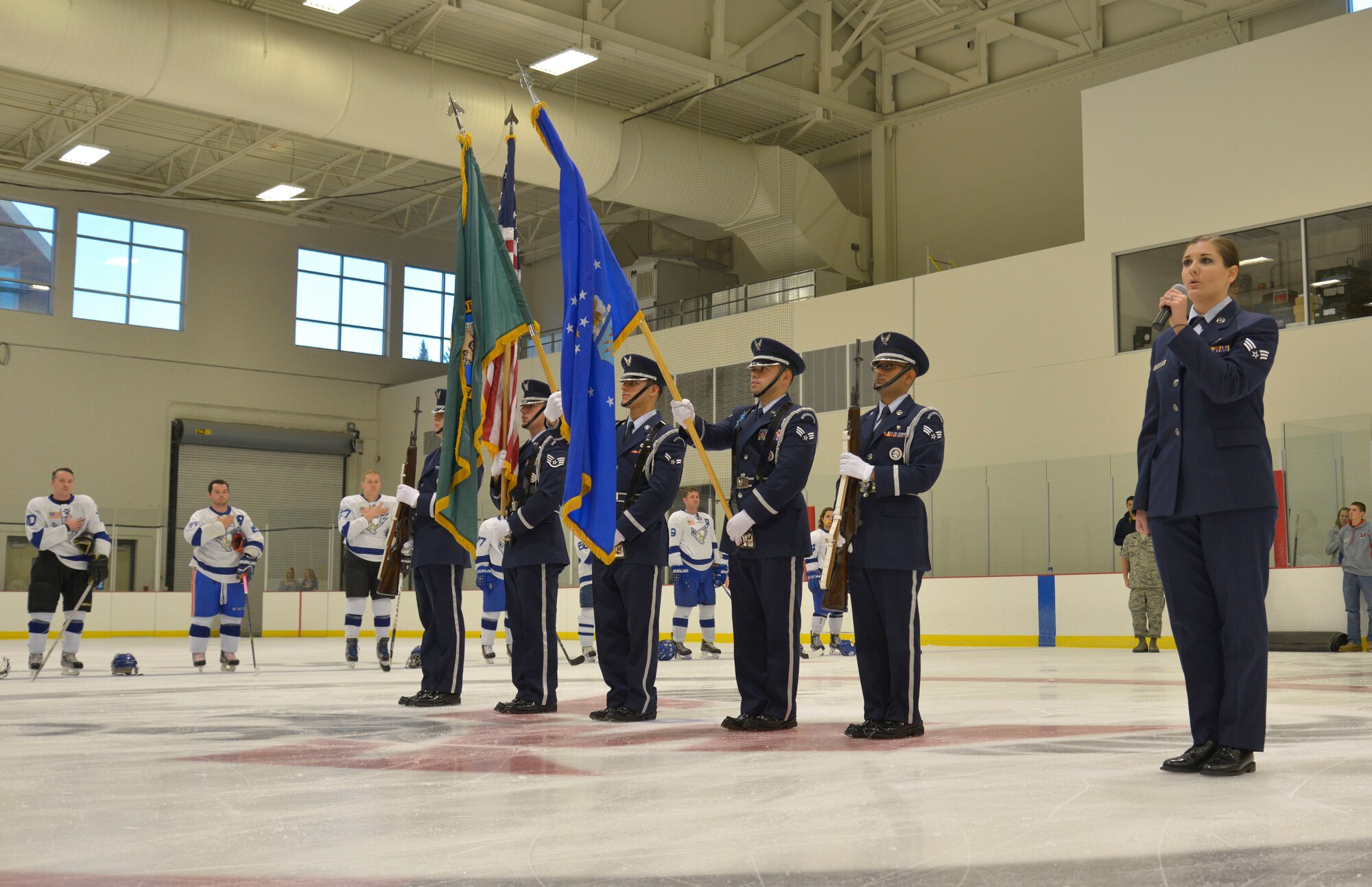 Senior Airman Kimberly Carter, 92nd Comptroller Squadron military pay technician, sings the National Anthem while the Fairchild Honor Guard presents the colors at the Blue vs. White Fairchild Falcons Varsity Hockey team game with Fairchild leadership coaching at Eastern Washington University’s Recreation Center in Cheney, Wash., Oct. 4, 2014. (U.S. Air Force photo by Airman 1st Class Janelle Patiño)