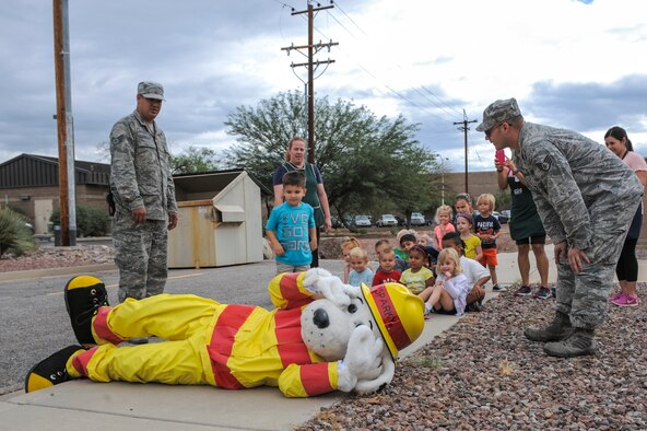 Sparky the Fire Dog, National Fire Protection Association spokesdog, and members from the 355th Fire Emergency Services flight teach children from the Child Development Center how to stop, drop and roll at Davis-Monthan Air Force Base, Ariz., Oct. 8, 2014. Sparky and pumper will be at the Child Development Center Oct. 6-7, 2015 for the 2015 Fire Prevention Week campaign. 