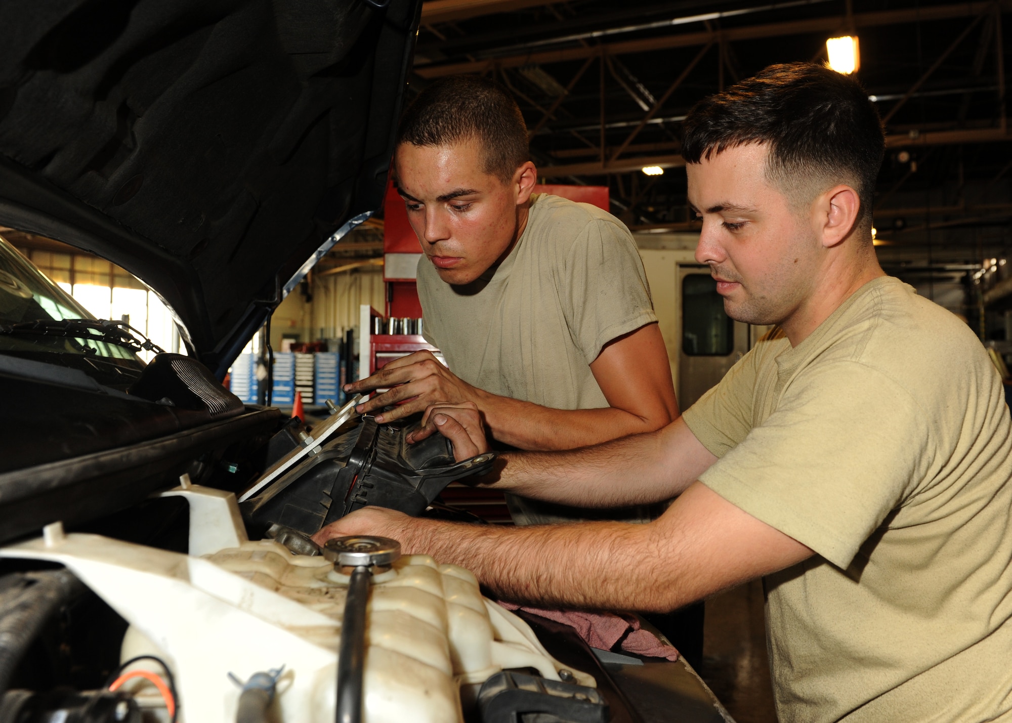 Airman 1st Class Chase Gibson and Airman 1st Class Ashton Rush-Jussila, both vehicle and vehicular equipment maintenance apprentices, reinstall an air filter assembly after replacing the serpentine belt on a Chevrolet step van Sept. 16, 2014, at Little Rock Air Force Base, Ark.  The 19th Logistics Readiness Squadron vehicle management flight maintains a 529-vehicle fleet. (U.S. Air Force photo by Airman 1st Class Scott Poe)