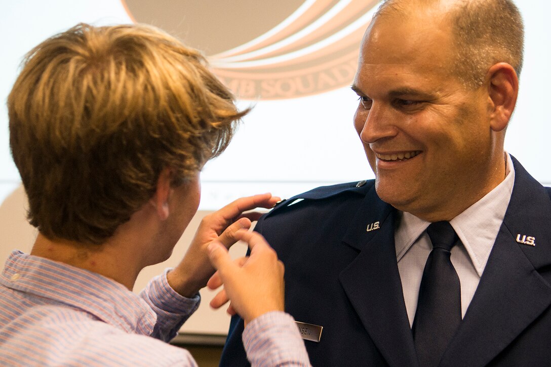 U.S. Air Force Col. Robert Simonsen is "pinned" by his son, Alex, during a promotion ceremony, Oct. 3, 2014, Barksdale Air Force Base, La. Simonsen is a B-52 Electronic Warfare Officer assigned to the 343rd Bomb Squadron and was recently promoted to the rank of Colonel. (U.S. Air Force photo by Master Sgt. Greg Steele/Released)