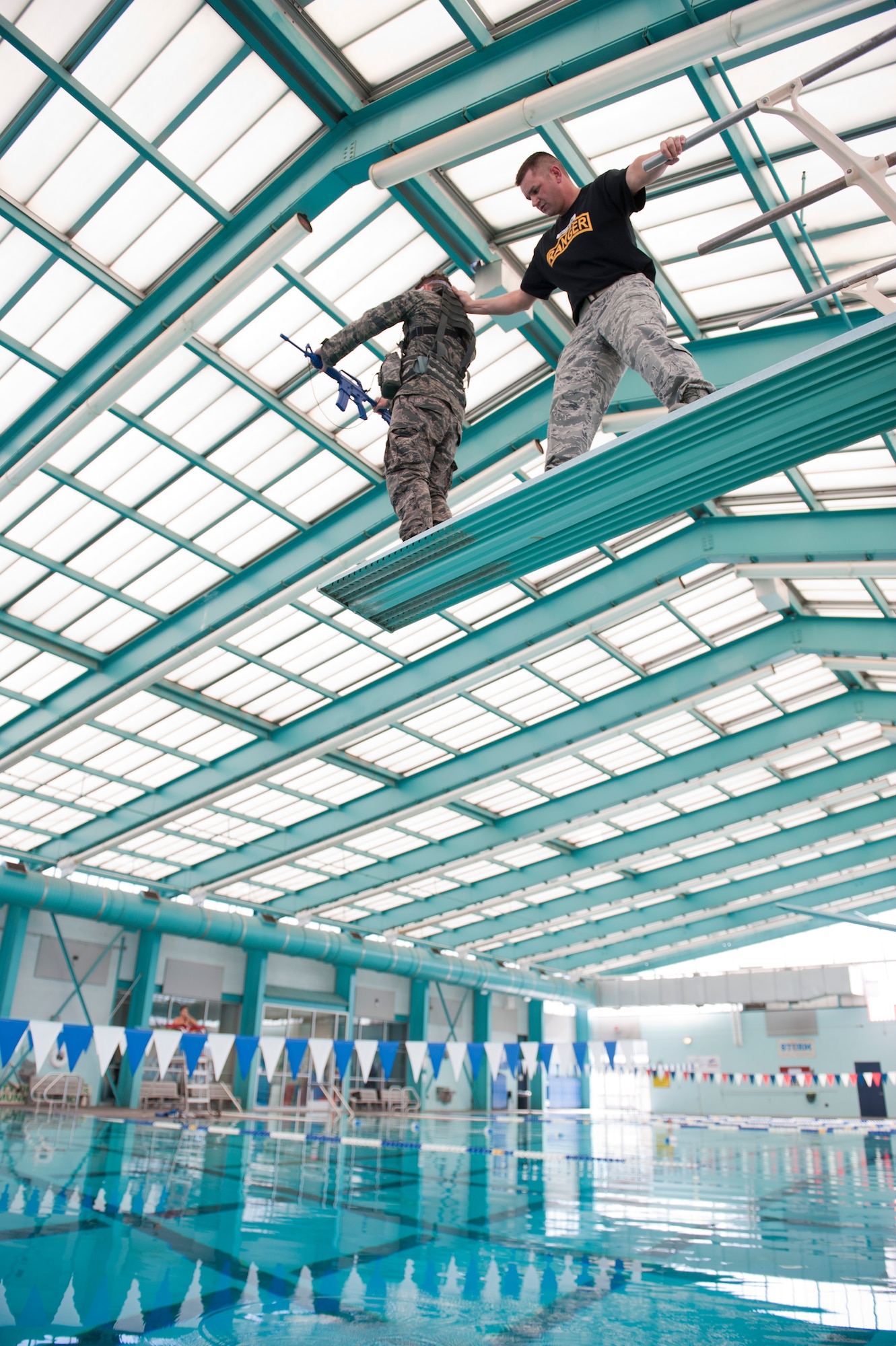 A Ranger Assessment Course instructor guides a RAC student to the edge of the three meter diving board before pushing the student off the board at the Municipal Pool, Las Vegas, Oct. 2, 2014. Before the student is pushed into the pool, he dons blacked-out goggles and is spun three times to cause disorientation. (U.S. Air Force photo by Airman 1st Class Thomas Spangler)