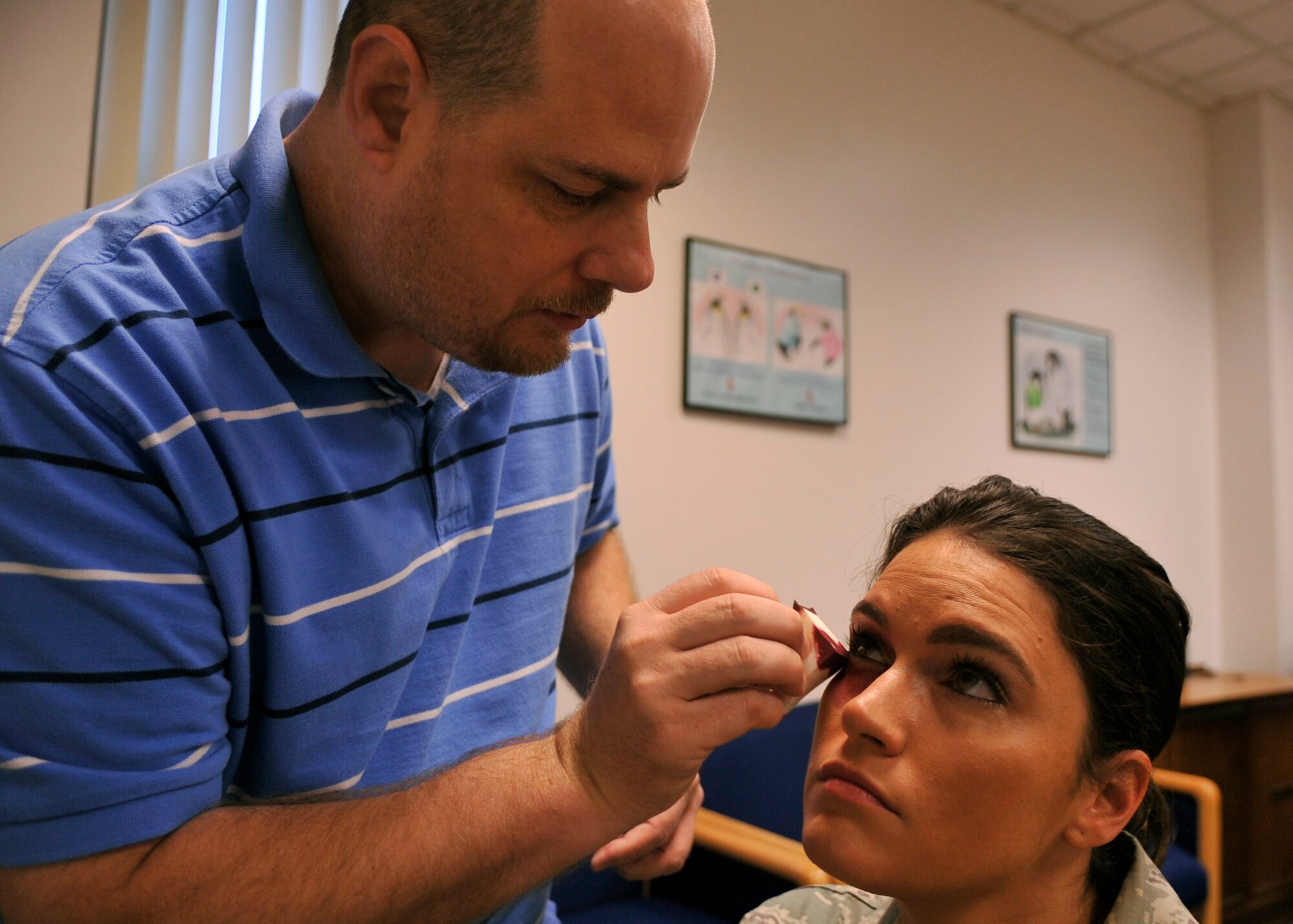 Phillip Calla, 325th Medical Support Squadron information technician, applies make-up to Staff. Sgt. Brittney Mendiola, 325 Civil Engineer Squadron base fire inspector, in preparation for the black eye campaign on Oct. 1 at Tyndall Air Force Base, Fla. The black eye campaign was done to raise awareness of domestic violence awareness month. (U.S. Photo by Airman 1st Class Ty-Rico Lea)