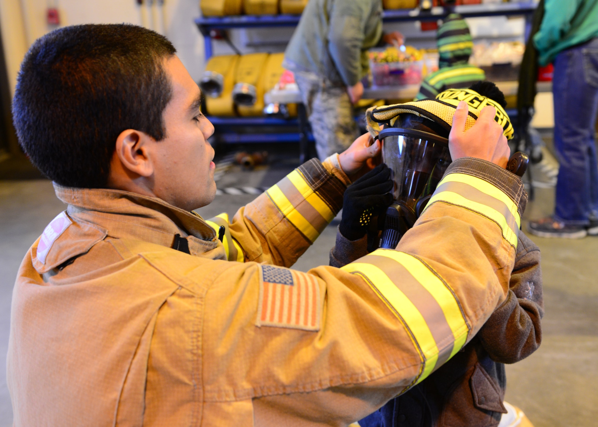 Airman 1st Class Israel Hernandez, 354th Civil Engineer Squadron firefighter, puts a fire mask on Camden Wyke during an open house at Fire Station 2 Oct. 5, 2014, Eielson Air Force Base, Alaska. Wyke, along with other children and Icemen families, spent the afternoon exploring the fire department and learned what firefighters do on a daily basis. (U.S. Air Force photo by Senior Airman Ashley Nicole Taylor/Released)