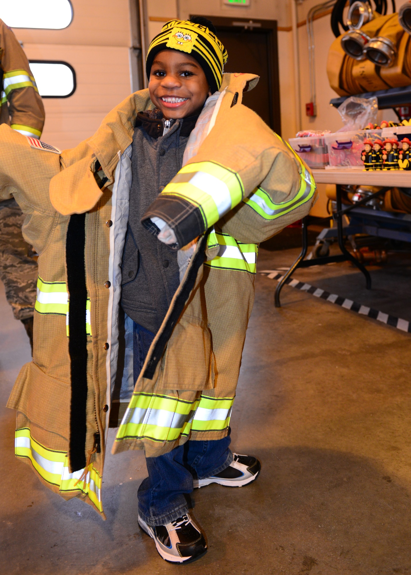 Camden Wyke tries on firefighter gear during an open house at Fire Station 2, Oct. 5, 2014, Eielson Air Force Base, Alaska. When all geared up, a firefighter’s uniform can weigh over 50 pounds. (U.S. Air Force photo by Senior Airman Ashley Nicole Taylor/Released)