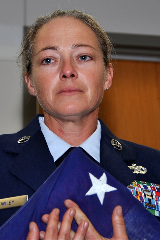 U.S. Air Force Master Sgt. Jessica Wiley, 307th RED HORSE Squadron, holds back the tears as she is presented the flag during her retirement ceremony Oct. 4, 2014, at Barksdale Air Force Base, La.  Wiley is retiring after 21 years of service. (U.S. Air Force photo by Master Sgt. Mary Hinson/Released)