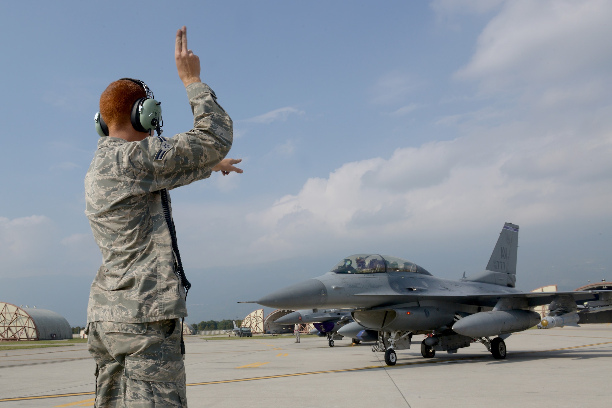 Airman 1st Class Matthew Galati, 31st Aircraft Maintenance Squadron crew chief, marshals an F-16 Fighting Falcon to taxi onto the flightline, Oct. 7, 2014, at Aviano Air Base, Italy. Aircraft marshalling is a visual signaling between ground personnel and pilots and serves as an alternative to radio communications. (U.S. Air Force photo/Airman 1st Class Ryan Conroy) 