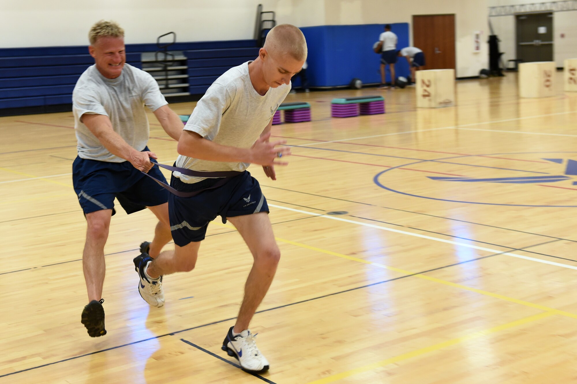 Staff Sgt. Dylan Williams, 460th Security Forces Squadron administrative NCO in charge, right, sprints across the gym as Chief Master Sgt. Craig S. Hall, 460th Space Wing command chief, holds him back with a resistance band during Hall’s last “Chief’s Workout” Oct. 7, 2014, at the fitness center on Buckley Air Force Base, Colo. The workout provided volunteers from different units an hour-long exercise session once a month that consisted of cardio and strength training exercises, as well as time with their command chief. (U.S. Air Force photo by Airman 1st Class Samantha Saulsbury/Released)