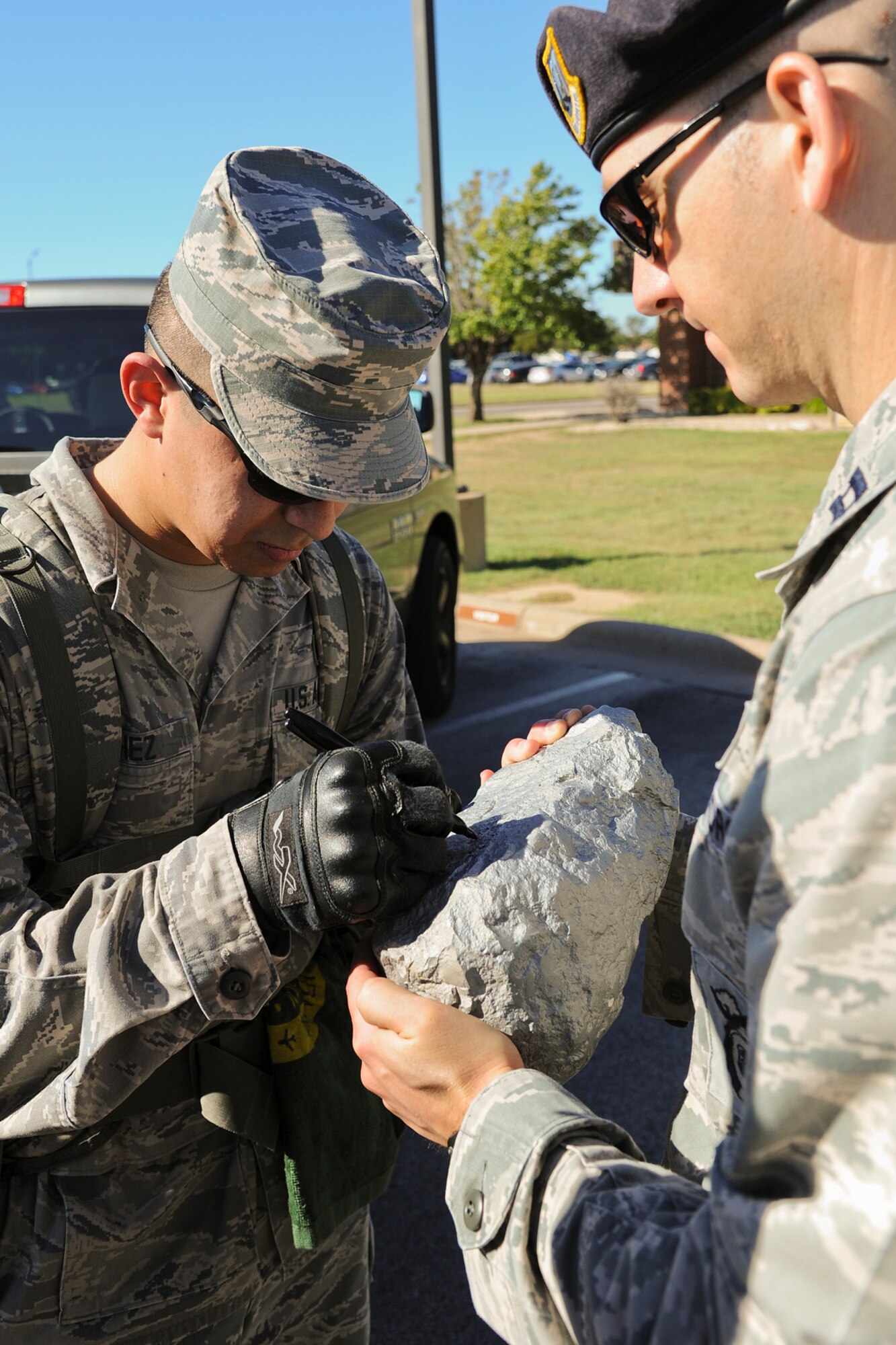 GOODFELLOW AIR FORCE BASE, Texas – Airman 1st Class Eduardo J. Sanchez, 17th Security Forces Squadron and ruck march participant, signs the Airman 1st Class Elizabeth Jacobson Rock held by Capt. James J. Nelson, 17th SFS Commander, during the 8th Annual Airman 1st Class Jacobson 4.1-Mile Memorial Ruck March at the 17th SFS parking lot Oct. 4. The individual who carries the rock in his/her ruck during the march gets to sign it. (Air Force photo/ Airman 1st Class Devin Boyer)