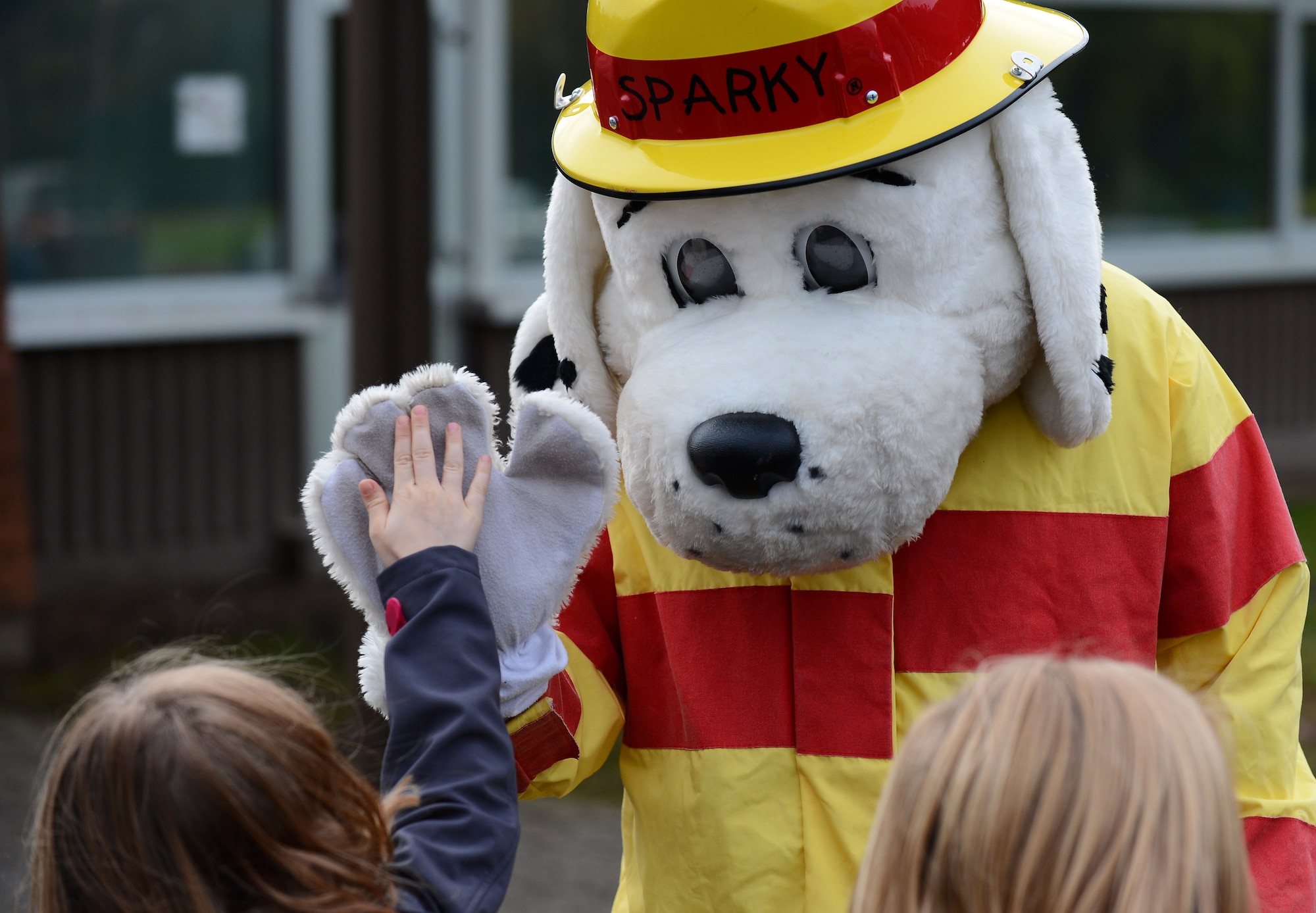 Sparky, the 52nd Civil Engineer Squadron firefighters’ mascot, high-fives a student during a visit from the CES firefighters at Spangdahlem Elementary School on Spangdahlem Air Base, Germany, Oct. 8, 2014. The firefighters demonstrated the importance of fire-safety to the students in observance of Fire Prevention Week. “A working smoke alarm saves lives” is this year’s theme. (U.S. Air Force photo by Airman 1st Class Luke J. Kitterman/Released)