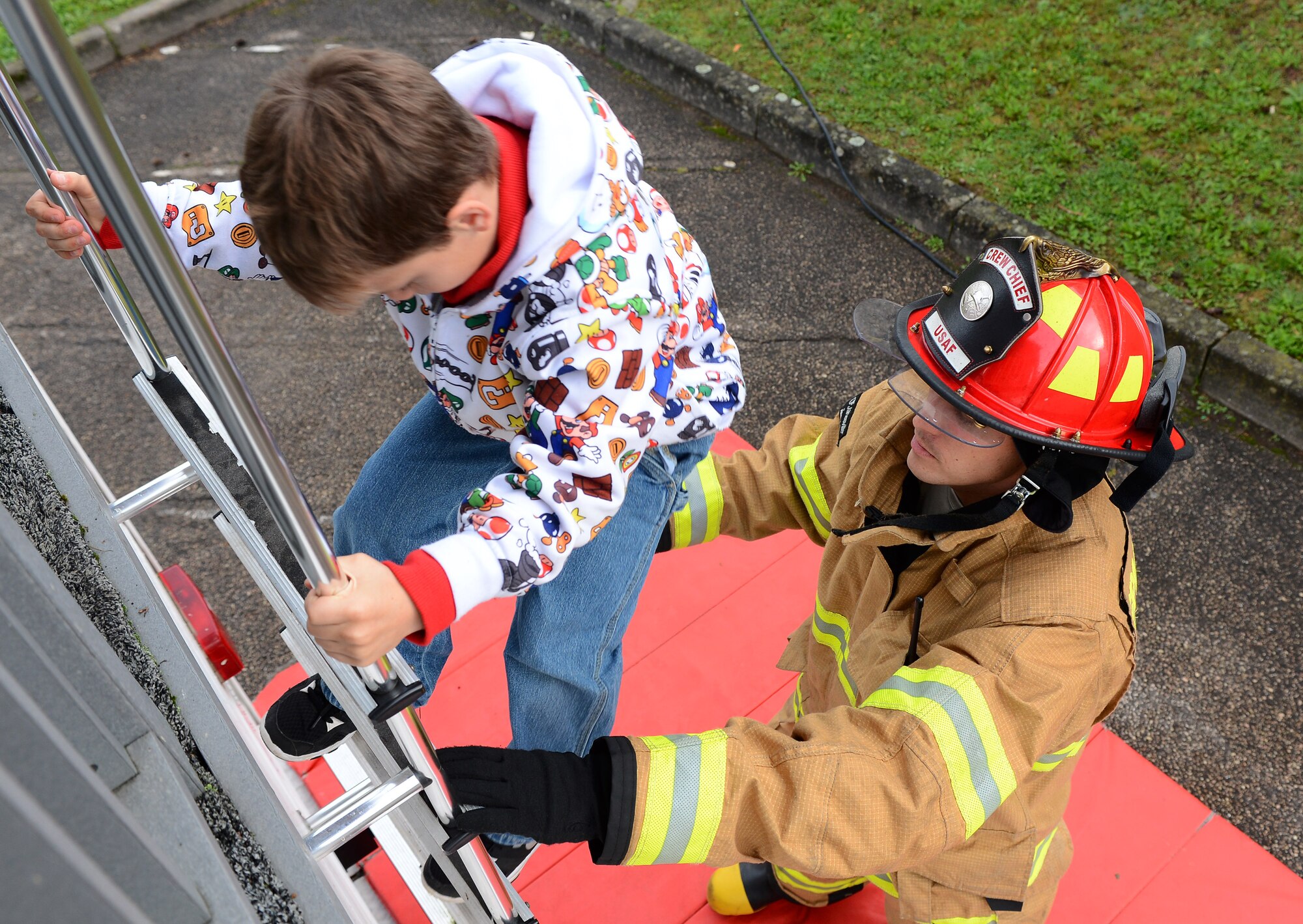 Landon Pace, son of U.S. Air Force Staff Sgt. Amy Dietrich, 52nd Logistics Readiness Squadron individual equipment element NCO in charge, climbs down a ladder into the hands of U.S. Air Force Tech. Sgt. Karl Schnoes, a 52nd Civil Engineer Squadron firefighter and native of Little Elm, Texas, during a simulated fire evacuation drill at SES at Spangdahlem Air Base, Germany, Oct. 8, 2014. Schnoes taught the students the importance of having a safe meeting place after escaping from a fire. (U.S. Air Force photo by Airman 1st Class Luke J. Kitterman/Released)