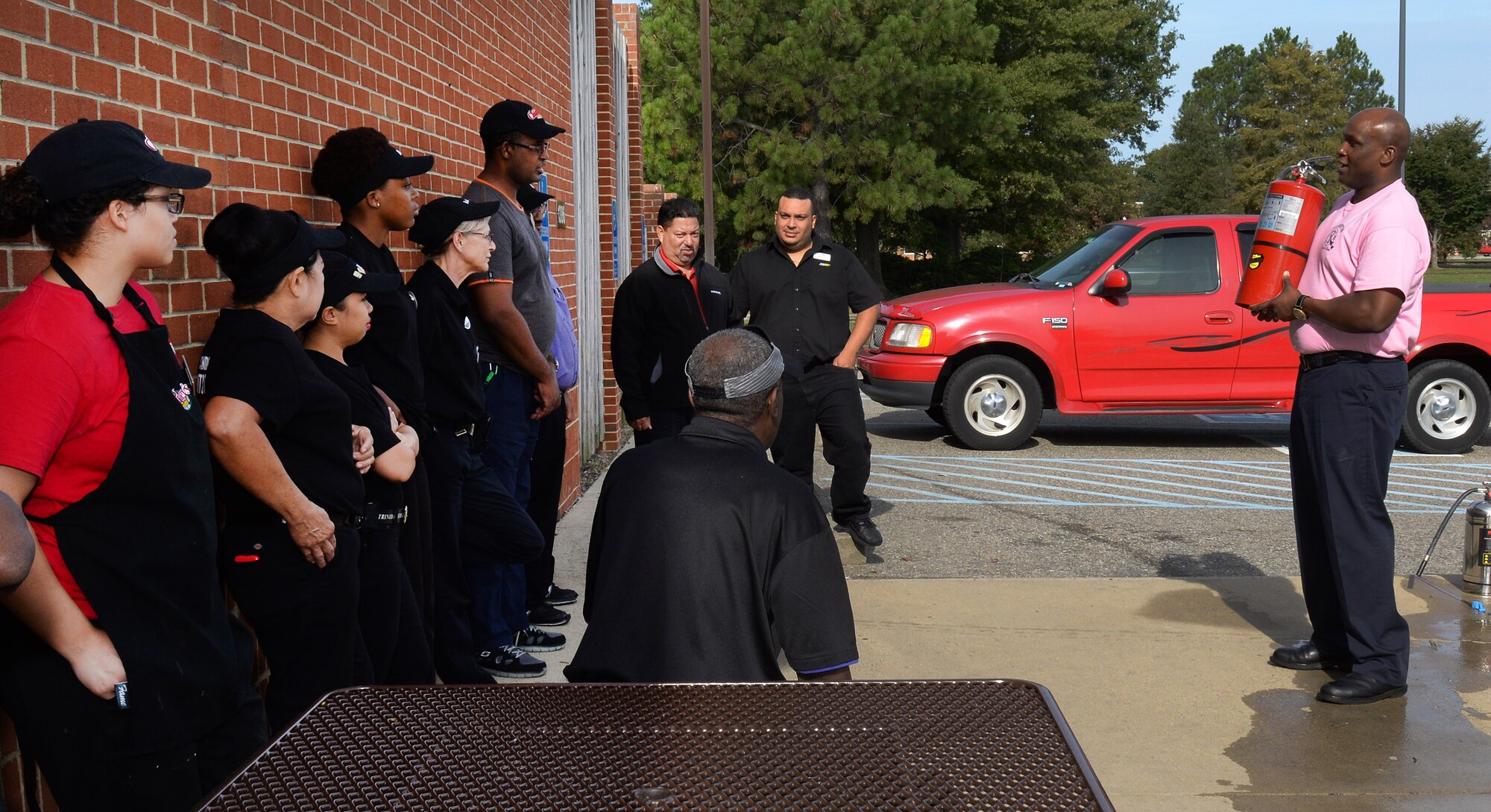 Keith Boyd, Fort Eustis Fire and Emergency Services inspector, instructs Exchange employees on proper use of a fire extinguisher during a demonstration at Fort Eustis, Va., Oct. 7, 2014.The exhibition was part of the department's Fire Prevention Week activities, designed to raise awareness about fire prevention and safety.  (U.S. Air Force photo by Staff Sgt. Teresa J. Cleveland/Released)