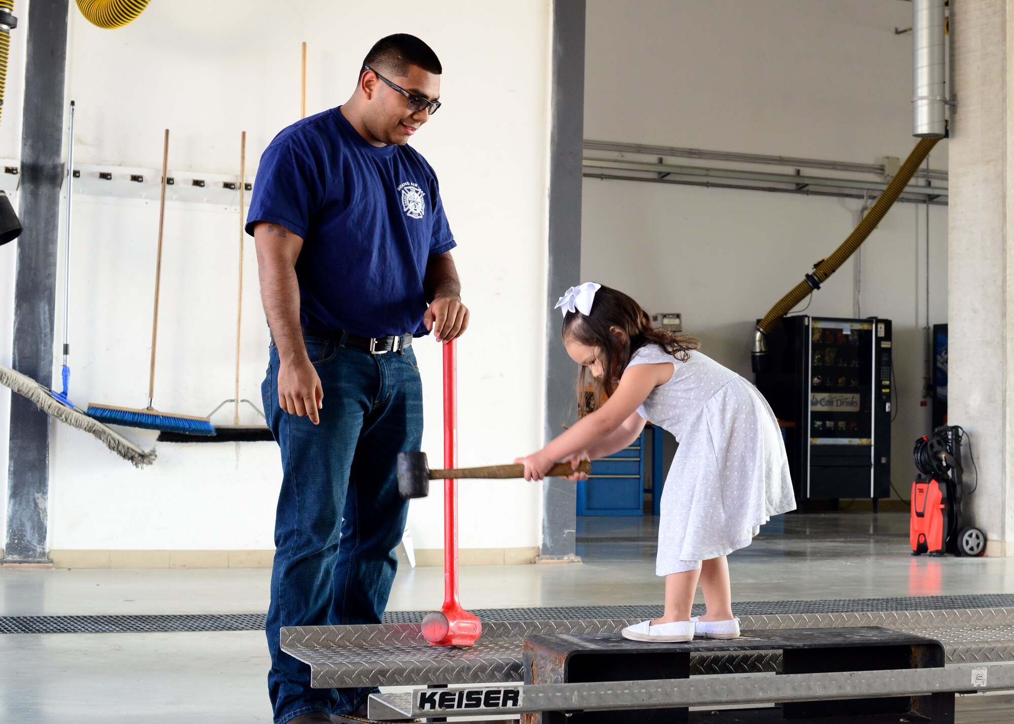 Senior Airman Manuel Rodriguez, 31st Civil Engineer Squadron firefighter, shows a child the proper way to strike a support beam during a fire department combat challenge, Oct. 5, 2014, at Aviano Air Base, Italy. In recognition of fire prevention week, fire fighters Aviano’s Fire Department hosted a series of events to educate children on fire safety, Oct. 5-11. (U.S. Air Force photo/Senior Airman Michael Battles)
