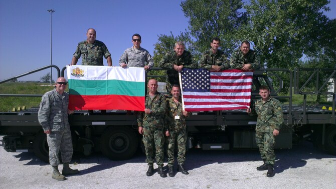 Staff Sgt. Jonathan Rasmussen, 48th Logistics Readiness Squadron transportation specialist from Royal Air Force Lakenheath, England (front left) and Staff Sgt. Luis Devotto, 435th Air Ground Operations Wing’s Contingency Readiness Group Air Advisor Branch air advisor special vehicle maintenance pose for a photo with members from two Bulgarian movement control teams on a Halvorsen Loader aircraft loader. Rasmussen and Devotto trained 16 members from the two teams on the operations and maintenance of a Halvorsen aircraft loader. (Courtesy photo)