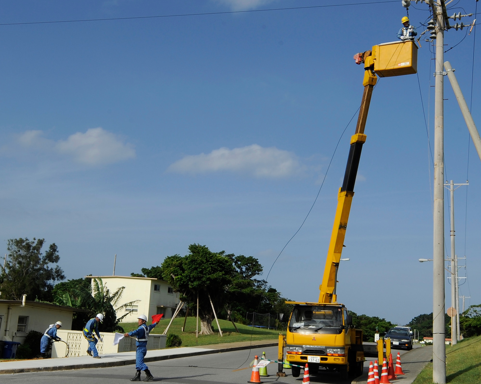 Air Force 718th Civil Engineer Squadron contractors take down overhead power lines on Kadena Air Base, Japan, Oct. 6, 2014. The lines are being replaced with underground power lines to protect them from the harsh environment which causes corrosion and increases the chance of power outages. (U.S. Air Force photo by Senior Airman Marcus Morris/Released)