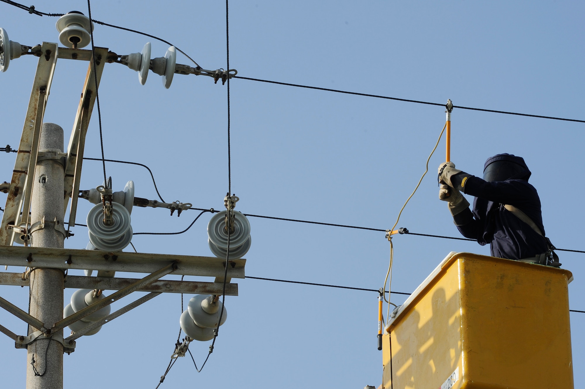 A contractor for the 718th Civil Engineer Squadron grounds overhead power lines to prevent accidental shock while working on Kadena Air Base, Japan, Oct. 6, 2014. The work was part of a project to replace Kadena’s overhead power lines with underground lines to mitigate exposure to the harsh environment which creates a higher risk for power failures, especially during typhoons. (U.S. Air Force photo by Senior Airman Marcus Morris/Released)