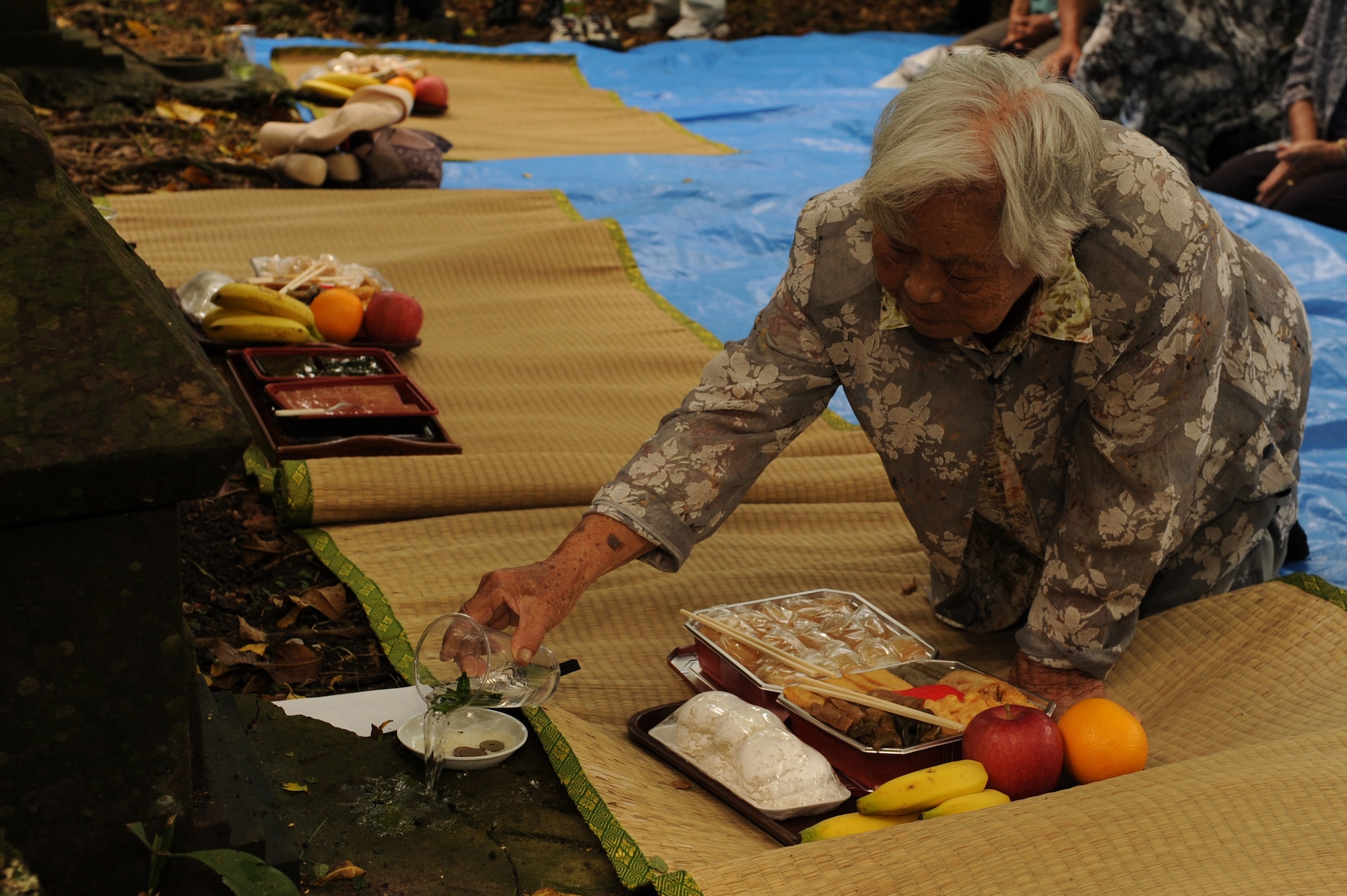 Shizuko Yara, an Okinawa City resident, pours sake onto a shrine as part of a Kikushu ritual on Kadena Air Base, Japan, Oct. 2, 2014. During Kikushu, members of any given Japanese community gather in a common space to offer food to their ancestors and pray for the prosperity of their families and a successful harvest. This year, former residents of the land Kadena now occupies came on base to visit their old community garden in celebration of Kikushu. (U.S. Air Force photo by Airman 1st Class Zade C. Vadnais/Released)  