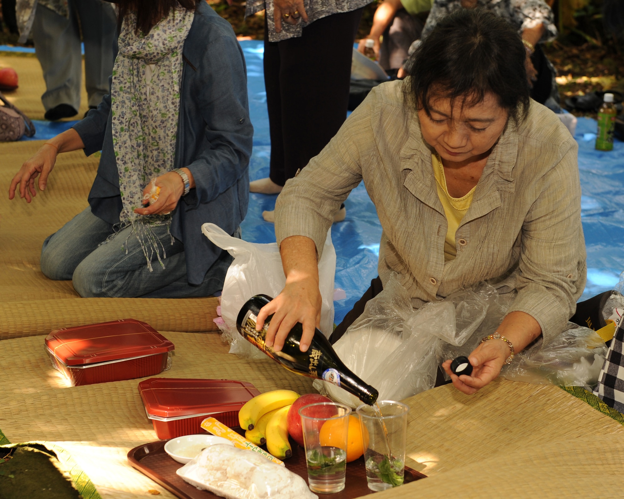 Junko Machida, an Okinawa City resident, pours sake into a cup in preparation for a Kikushu ritual on Kadena Air Base, Japan, Oct. 2, 2014. Kikushu is a traditional Japanese celebration where members of a community gather in a common area to offer food to their ancestors and pray for a successful harvest and their family's prosperity. This year, former residents of the land Kadena now occupies came on base to visit their old community garden and celebrate Kikushu. (U.S. Air Force photo by Airman 1st Class Zade C. Vadnais/Released)