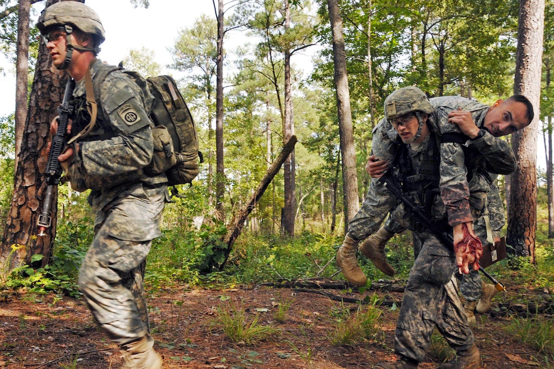 Soldiers conduct a tactical movement while transporting a simulated casualty during the combat testing lanes portion of the All-American Best Medic Competition on Fort Bragg, N.C., Oct. 7, 2014.