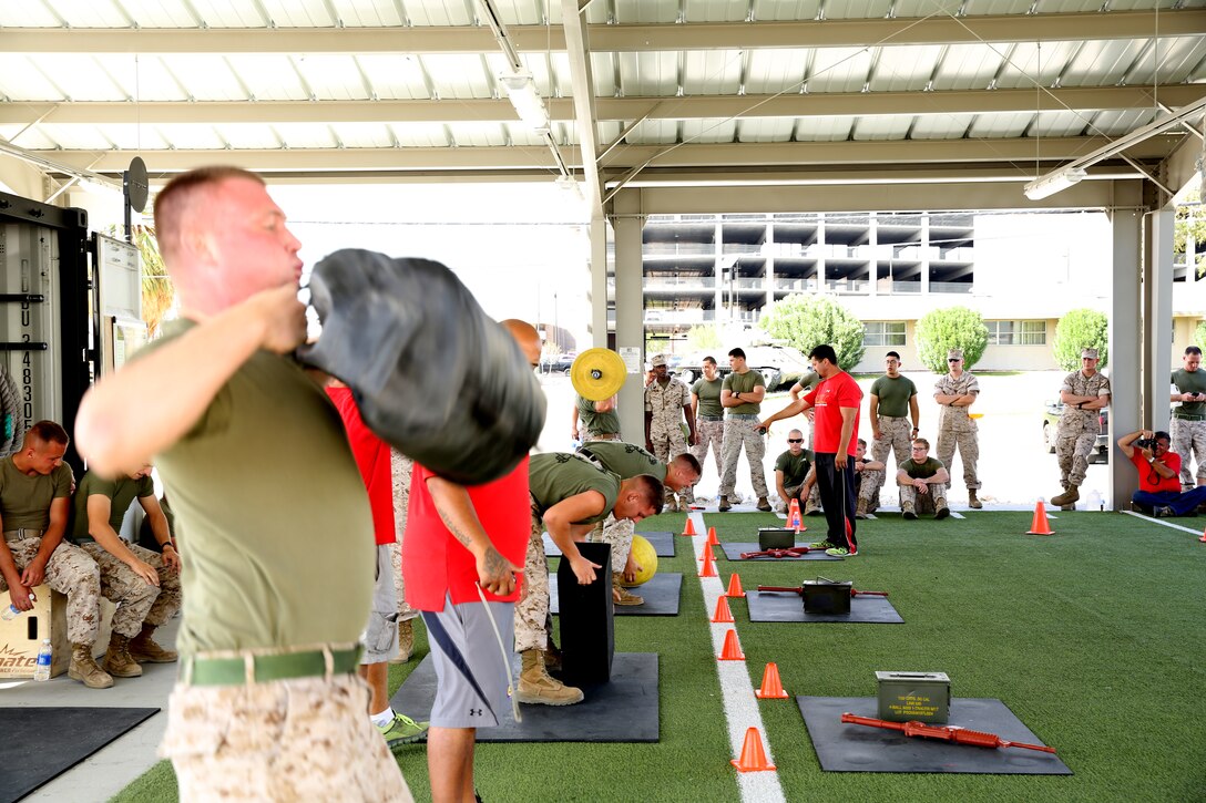 Marines with Marine Wing Support Squadron 374 conduct the overhead weight-lifting challenge as part of the Warrior Games at the West Gym aboard the Combat Center, Oct. 7, 2014. Each team consisted of four service members who would lift each object 10 times before going to a weapon simulator to test hand-eye coordination.