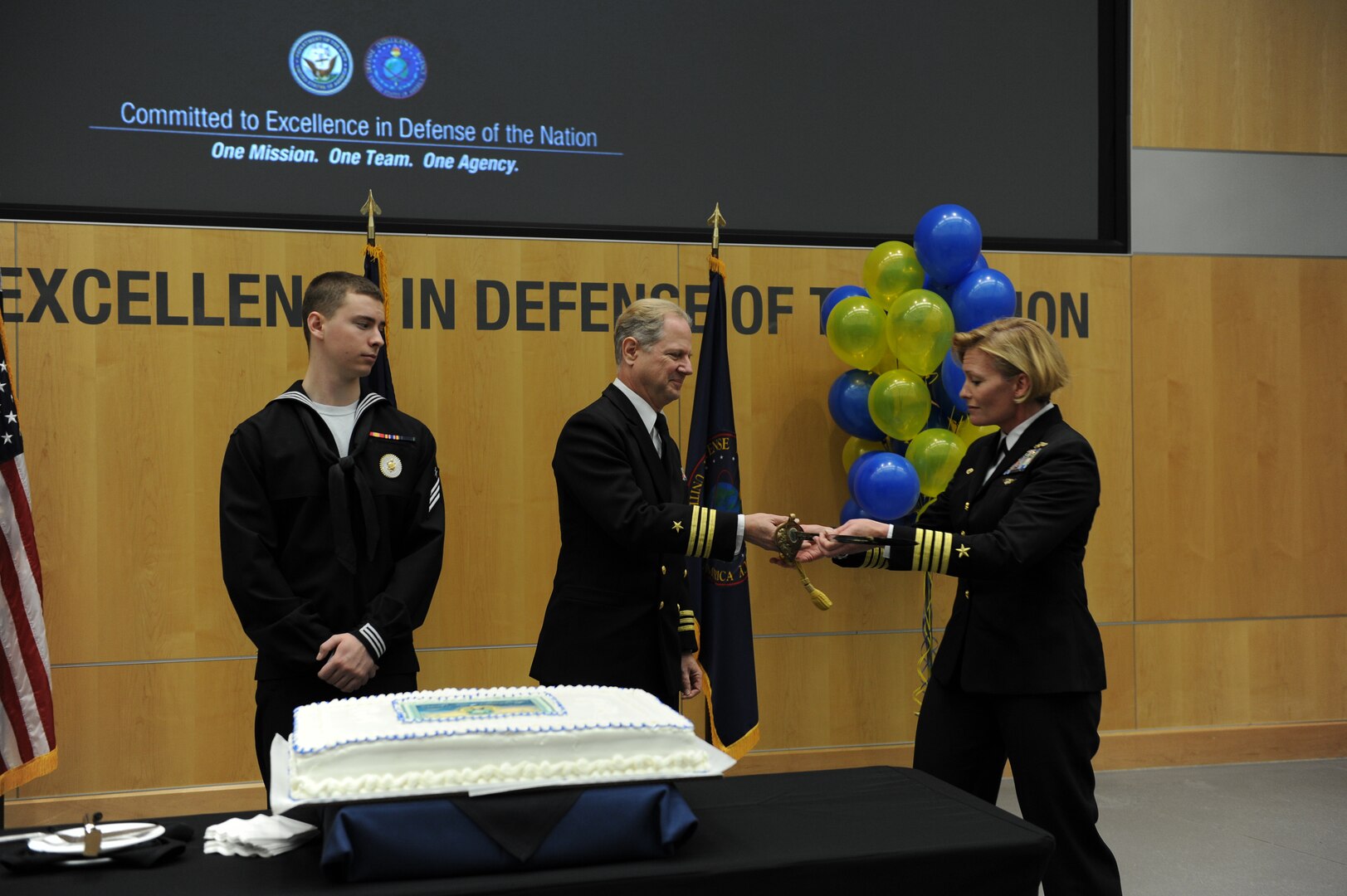 Capt. Heidi Berg, commanding officer of DIA’s Navy element, passes her family’s sword to DIA’s oldest Navy member for the time-honored tradition of cake cutting by the oldest and youngest sailors in the command. 