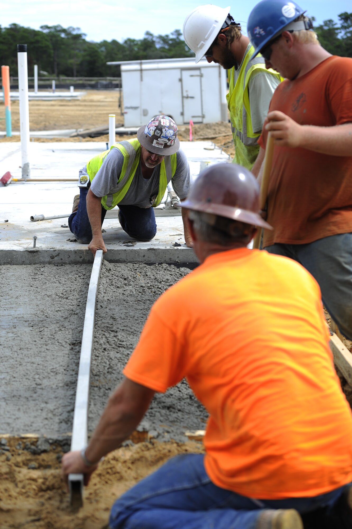 Construction workers use a straightedge to strike off freshly placed concrete at the construction site for the future Osprey neighborhood on Hurlburt Field, Fla., Oct. 2, 2014. Straightedges are used to “strike off” or “screed” concrete, this process removes excess concrete to make it as level as possible before finishing. (U.S. Air Force photo/Staff Sgt. Sarah Hanson)