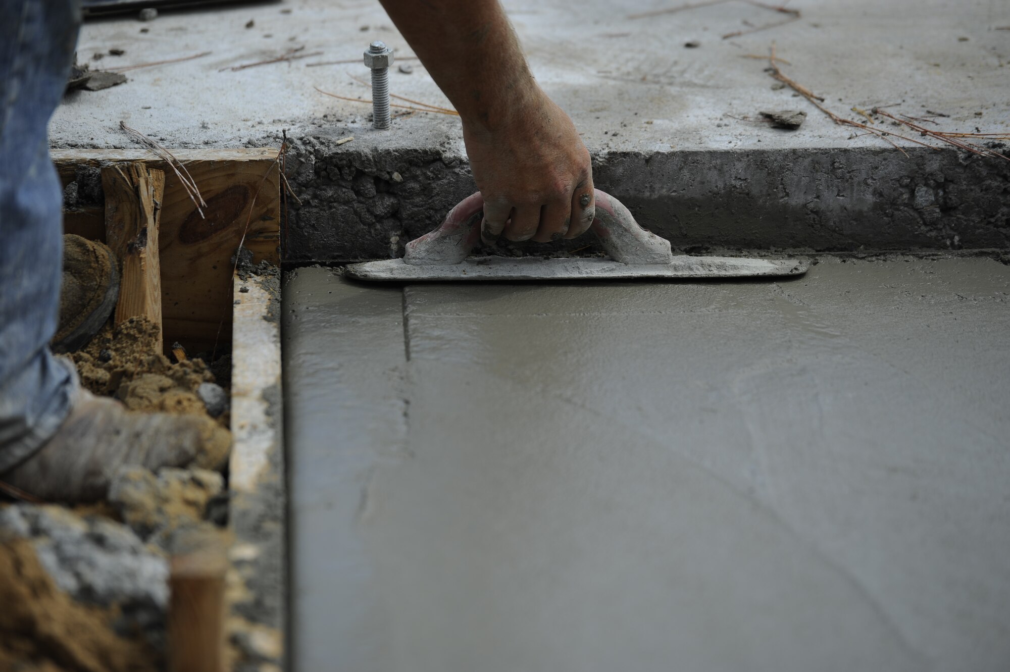 A construction worker uses a magnesium float to level the surface of poured concrete for the future Osprey neighborhood on Hurlburt Field, Fla., Oct. 2, 2014. The concrete pad will be a back porch of a new single senior non-commissioned officer home.  (U.S. Air Force photo/Staff Sgt. Sarah Hanson)
