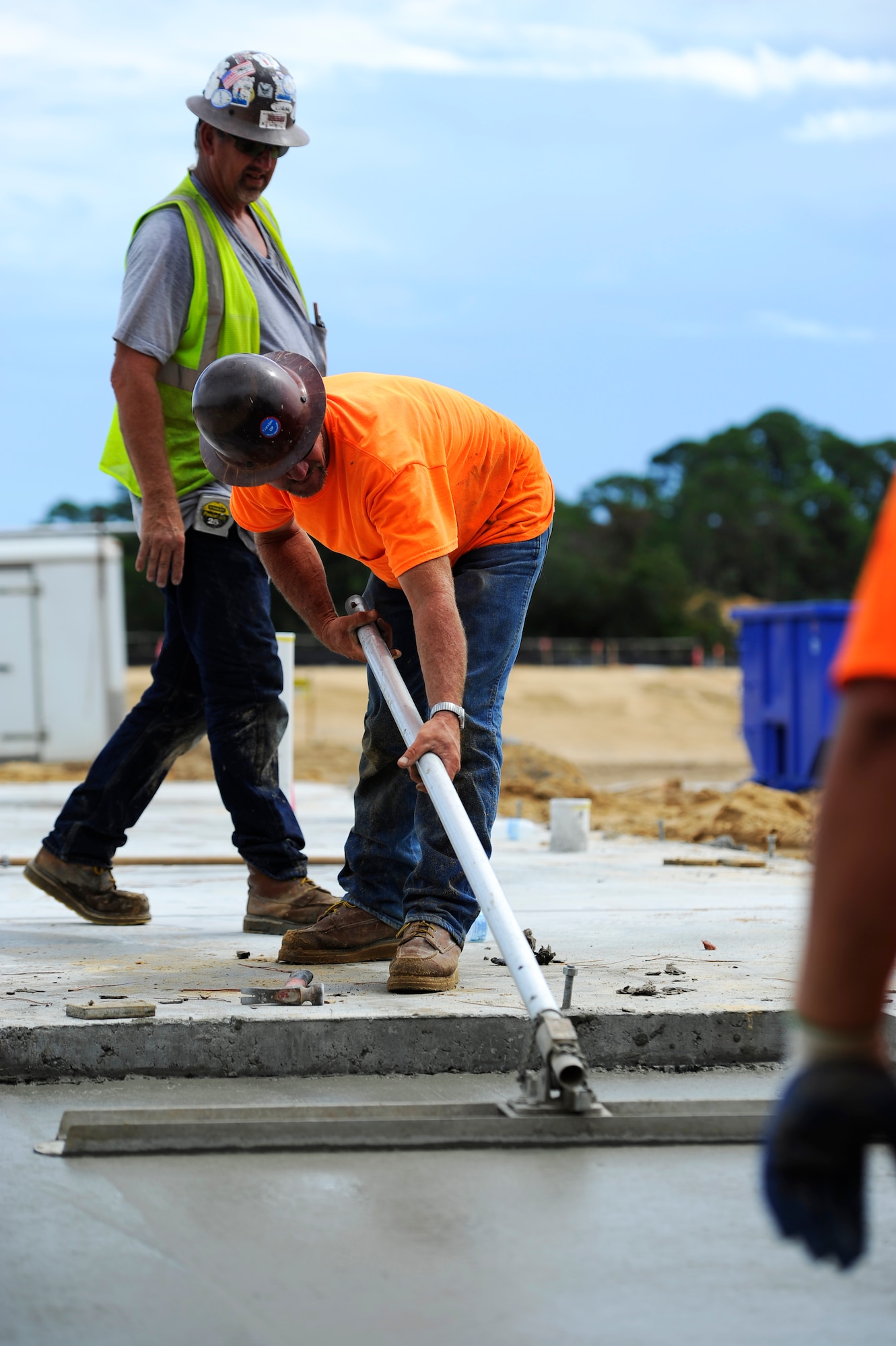 Construction workers use a concrete squeegee to spread concrete at the construction site for the future Osprey neighborhood on Hurlburt Field, Fla., Oct. 2, 2014. The concrete pad will be a back porch of a new single senior non-commissioned officer home.  (U.S. Air Force photo/Staff Sgt. Sarah Hanson)