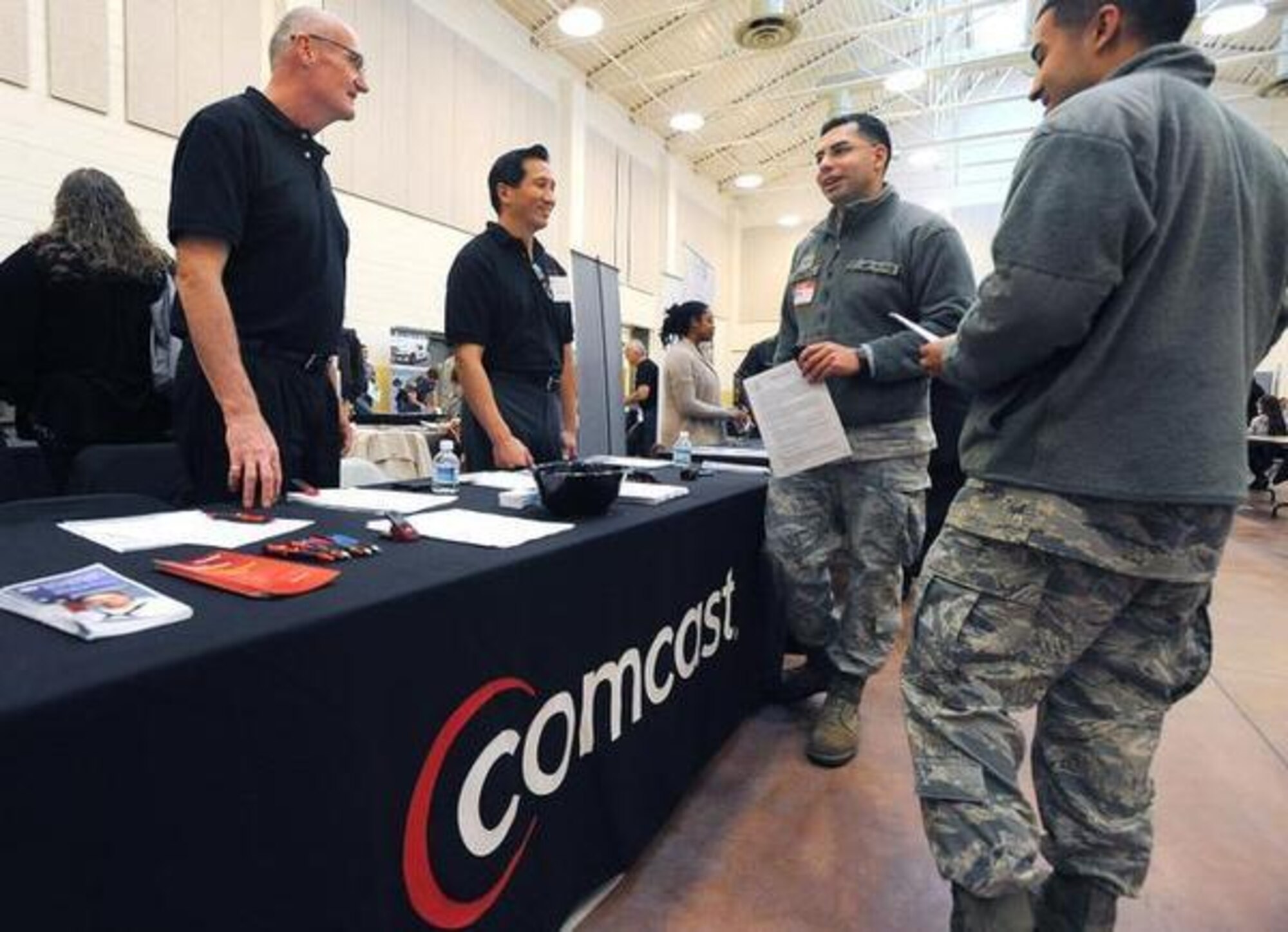 Senior Airman Christian Espinoza (middle), 627th Security Forces Squadron member, and Senior Airman Sam Thorpe (right), 627th SFS member, talk with representatives from Comcast about career opportunities with the Philadelphia-based mass media and communications company during a recent career fair at the Washington National Guard's new readiness center at Joint Base Lewis-McChord, Wash. (Courtesy photo) 