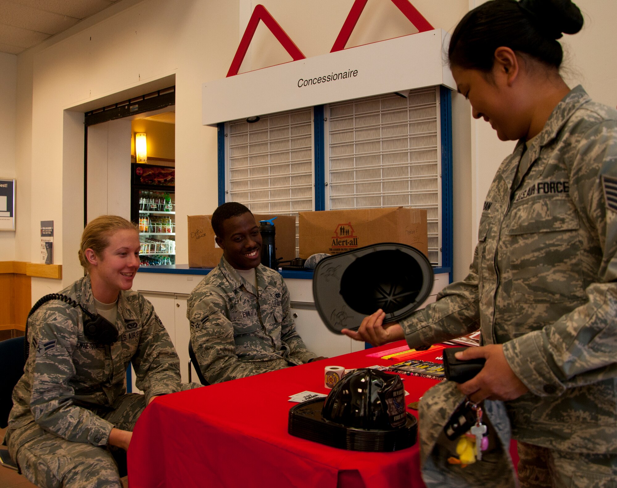 Airman 1st Class Piper Whetstone and Airman 1st Class Lejarrell Evans 90th Civil Engineer firefighters, give out fire prevention information and memorabilia to Tech. Sgt. Renelyn Pagan, 90th Medical Operations Squadron NCO-in-charge of pediatrics, Oct. 8, 2014, in the F.E. Warren Base Exchange. Whetstone, Evans and their wingmen set up the display in the BX for National Fire Prevention Week. (U.S. Air Force photo by Senior Airman Jason Wiese)