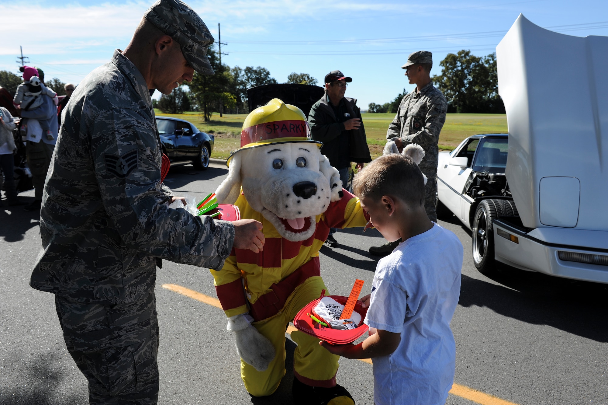 Staff Sgt. Zach Colburn and Sparky pass out candy and toys to a child during Rocktoberfest Oct. 4, 2014, at Little Rock Air Force Base, Ark. Rocktoberfest provided several different activities for all in attendance, including a car show and live entertainment. (U.S. Air Force photo by Staff Sgt. Jessica Condit)