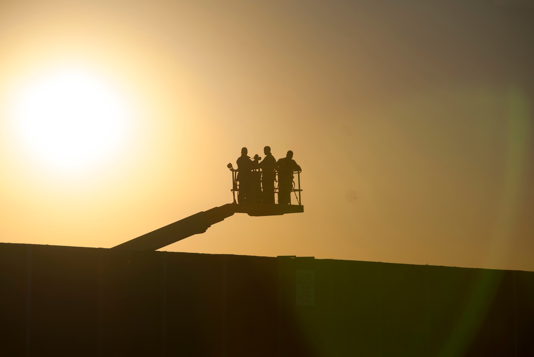 Silhouetted against a Tucson morning sky on a boom lift, 162nd Wing public affairs specialists prepare for a day of photo shooting on Oct. 5, at the Tucson International Airport. The day started with a wing portrait, followed by smaller, group-level and section pictures throughout the day. “The 162nd Wing is not just an incredible team, but a close-knit family,” said Col. Phil Purcell, wing commander. “What better way to capture that spirit, and the importance of our global mission sets, than family photos.” (U.S. Air National Guard photo taken by Staff Sgt. Heather Davis)