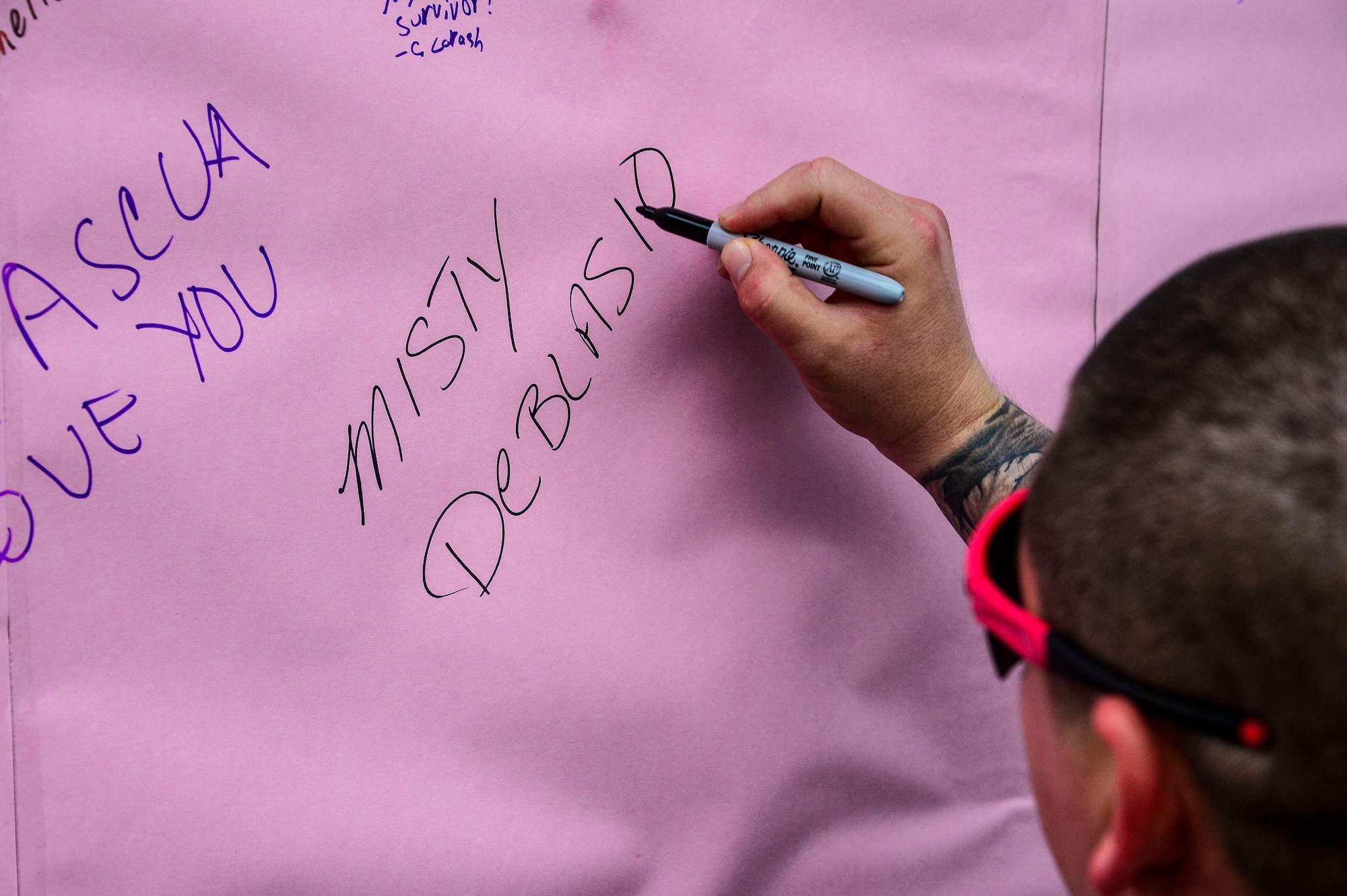 U.S. Army Sgt. India Smith, assigned to the 1-228th Aviation Regiment, writes the name of the person she ran in support of on a poster during the “Think Pink 5K” on Soto Cano Air Base, Oct. 9, 2014.   The fun run was planned and coordinated by the Morale, Welfare, and Recreation Center to help increase breast cancer awareness. (U.S. Air Force photo by Tech. Sgt. Heather R. Redman/Released)