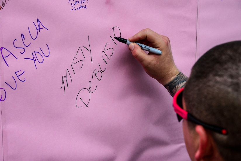 U.S. Army Sgt. India Smith, assigned to the 1-228th Aviation Regiment, writes the name of the person she ran in support of on a poster during the “Think Pink 5K” on Soto Cano Air Base, Oct. 9, 2014.   The fun run was planned and coordinated by the Morale, Welfare, and Recreation Center to help increase breast cancer awareness. (U.S. Air Force photo by Tech. Sgt. Heather R. Redman/Released)