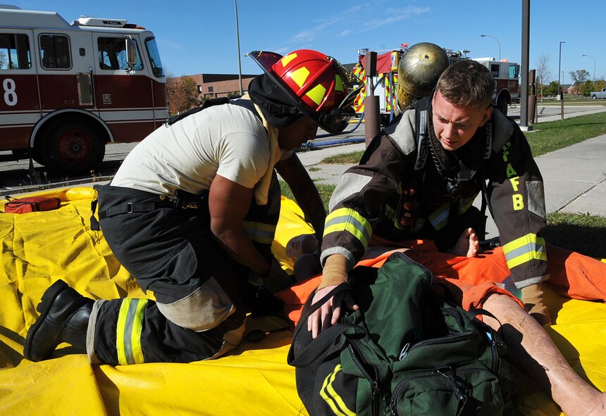 Staff Sgt. Koree Eichelberger (left), 319th Civil Engineer Squadron fire protection crew chief, and Airman 1st Class Scott Miller, 319th CES firefighter apprentice, prepare to perform self-aid and buddy care on a mannequin pulled out of a simulated fire during a fire training exercise Oct. 8, 2014, at Grand Forks Air Force Base, N.D. The exercise took place as a part of Fire Prevention Week, emphasizing the importance of fire prevention and safety. (U.S. Air Force photo/Airman 1st Class Bonnie Grantham)